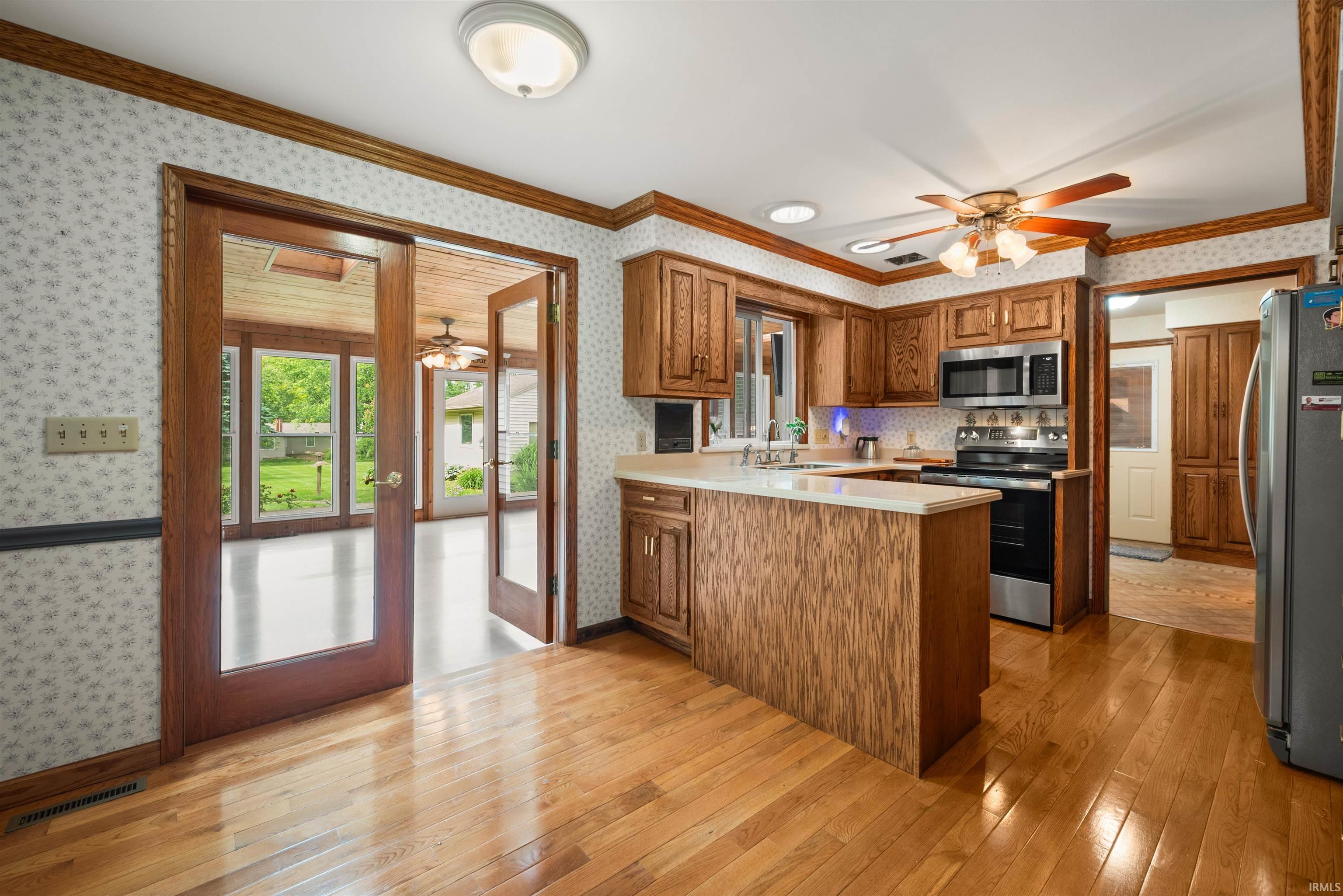 Kitchen featuring wood-finish flooring, wood cabinetry, stainless steel appliances, and a central island with countertop seating