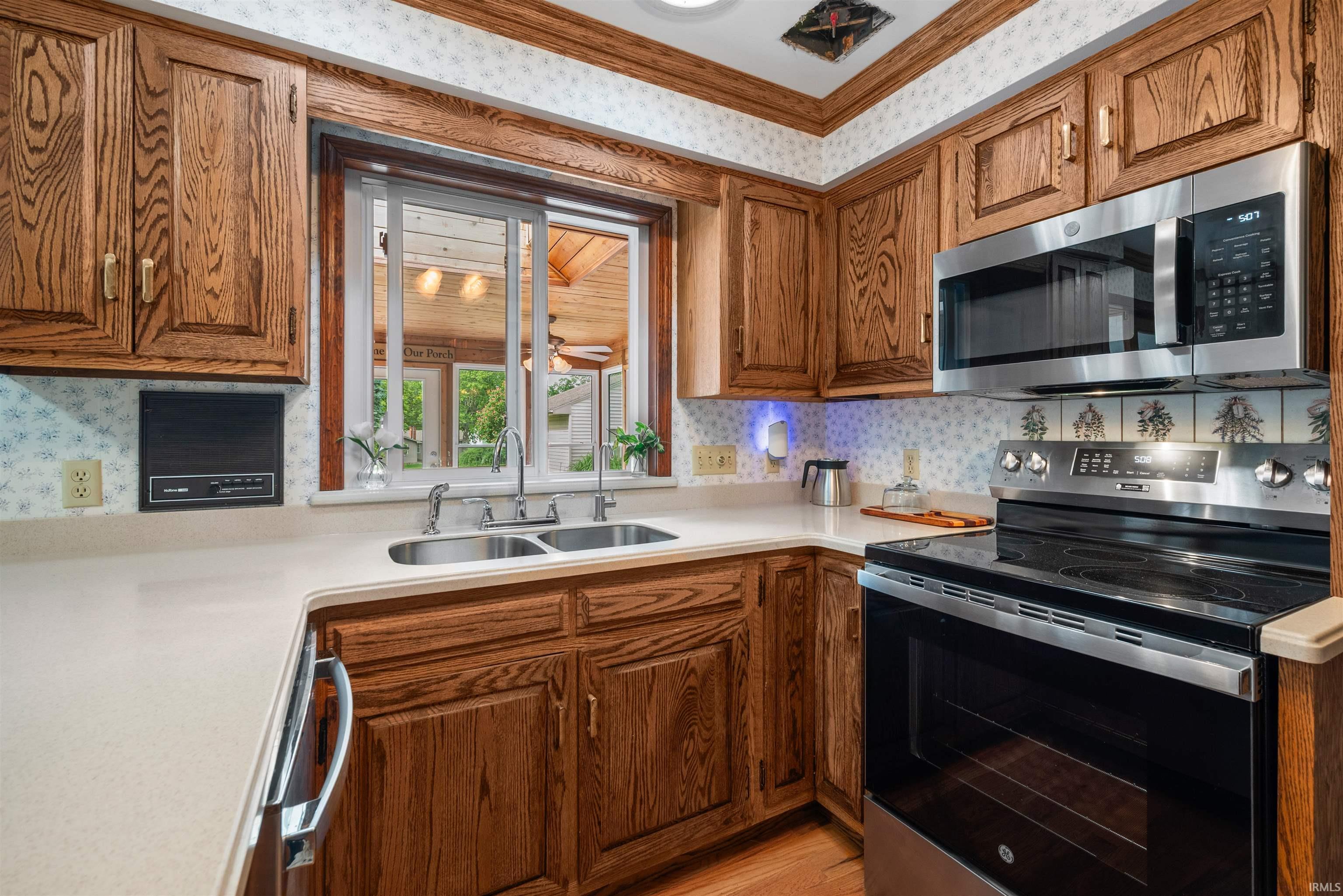 Kitchen featuring wood cabinetry, stainless steel appliances, a double basin sink, and ample countertop space