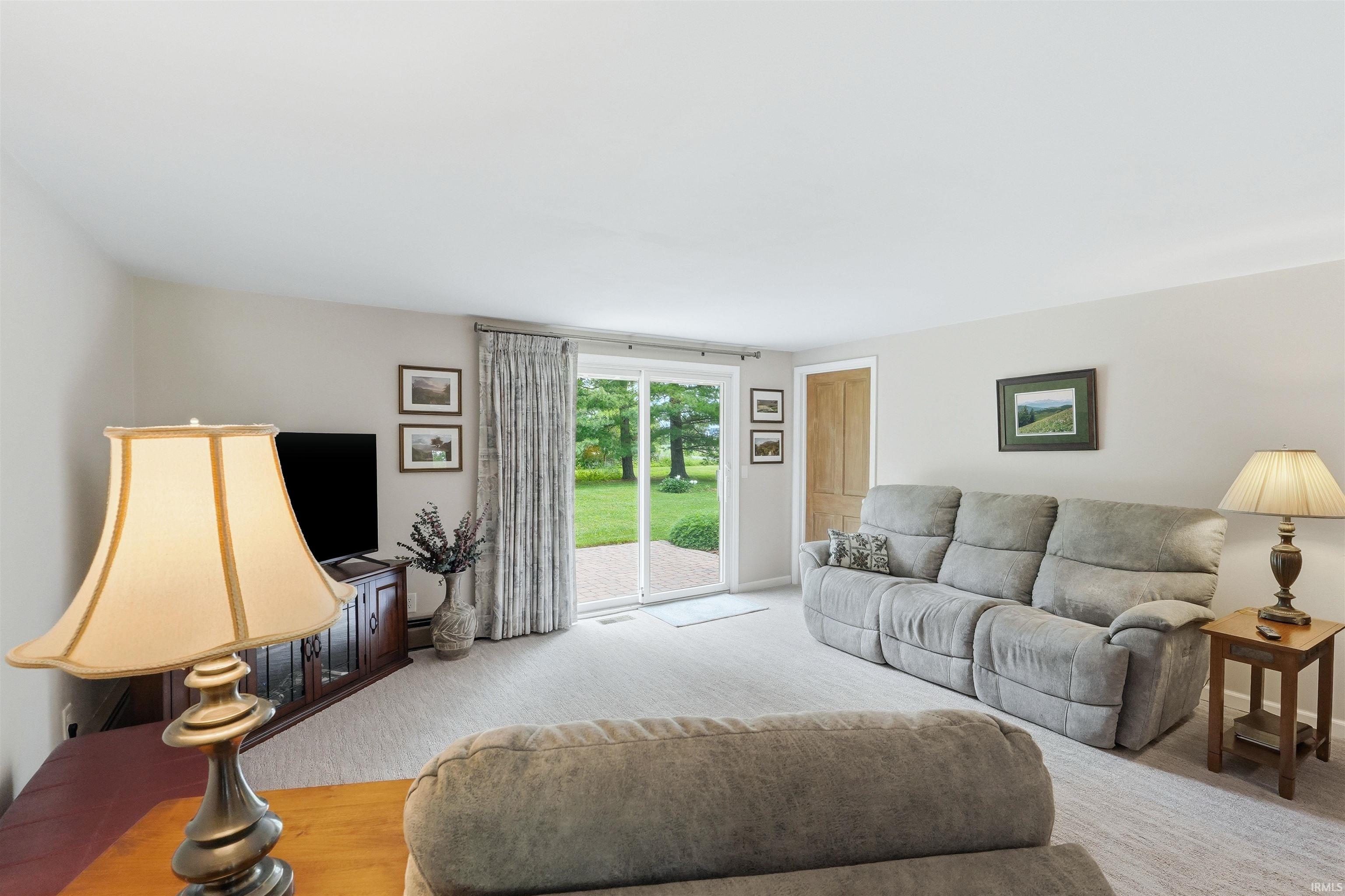 Carpeted living area featuring light-toned walls and a sliding glass door