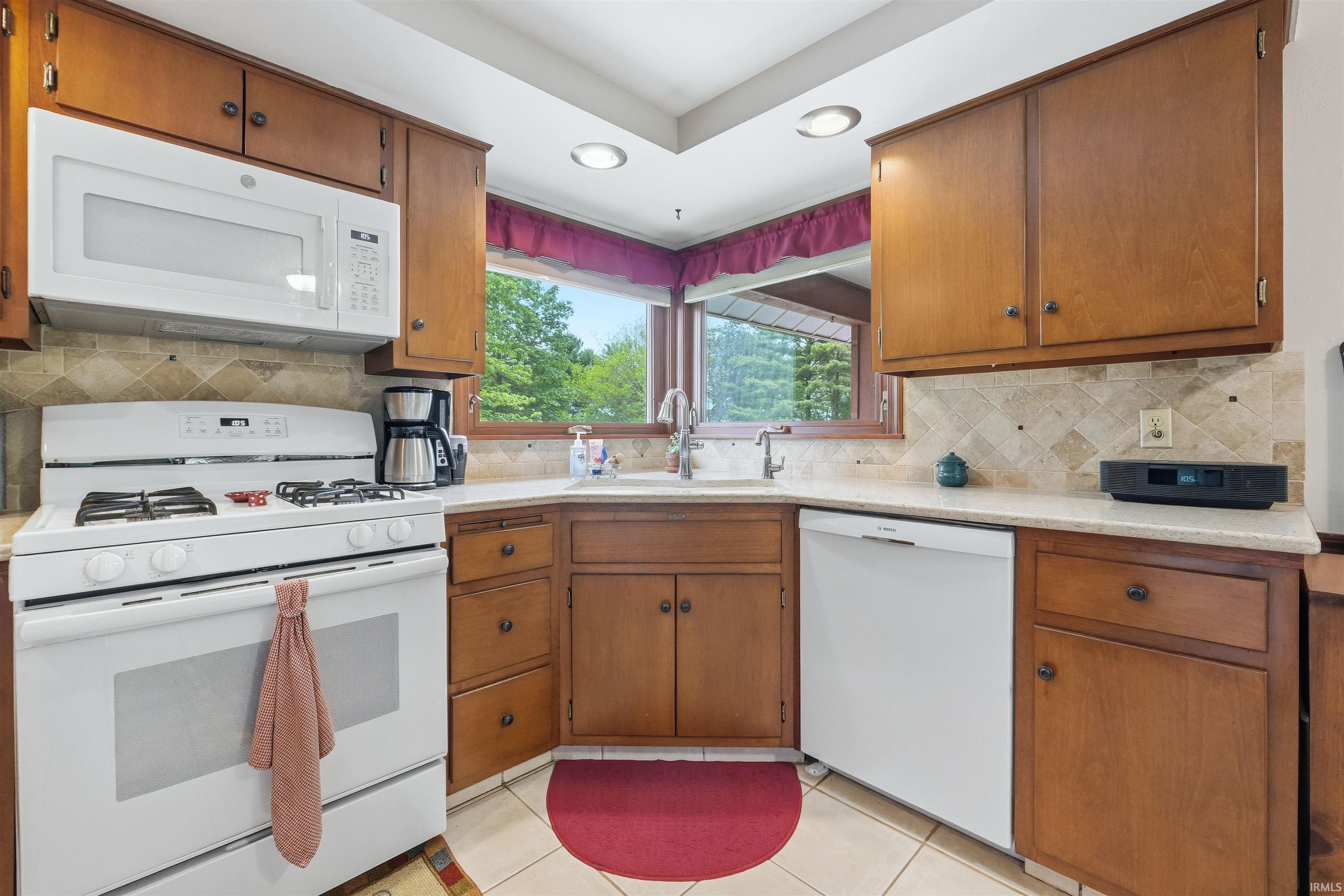 Kitchen featuring wood cabinetry, light-toned countertops, and a tiled backsplash