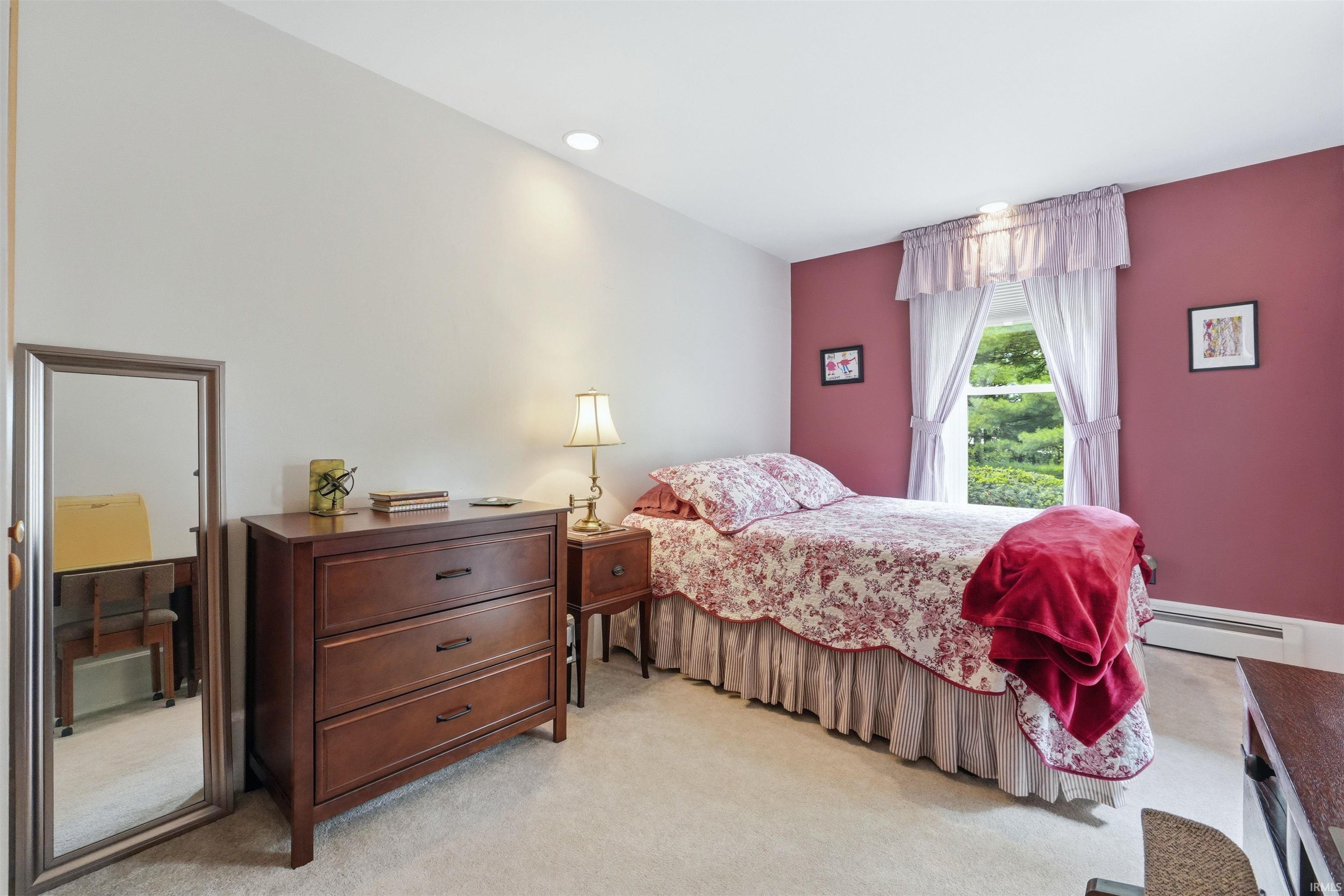 Carpeted room featuring a window with natural light, recessed ceiling lighting, and a baseboard heating unit