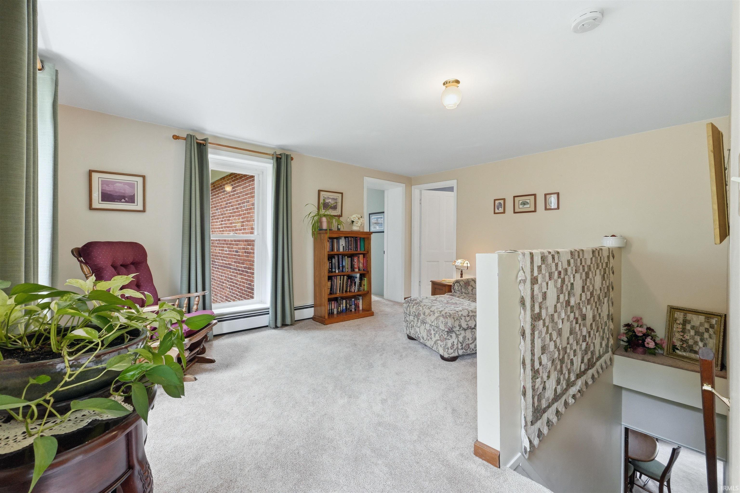 Carpeted upper level with a prominent window, ceiling light fixture, and warm-toned wall paint