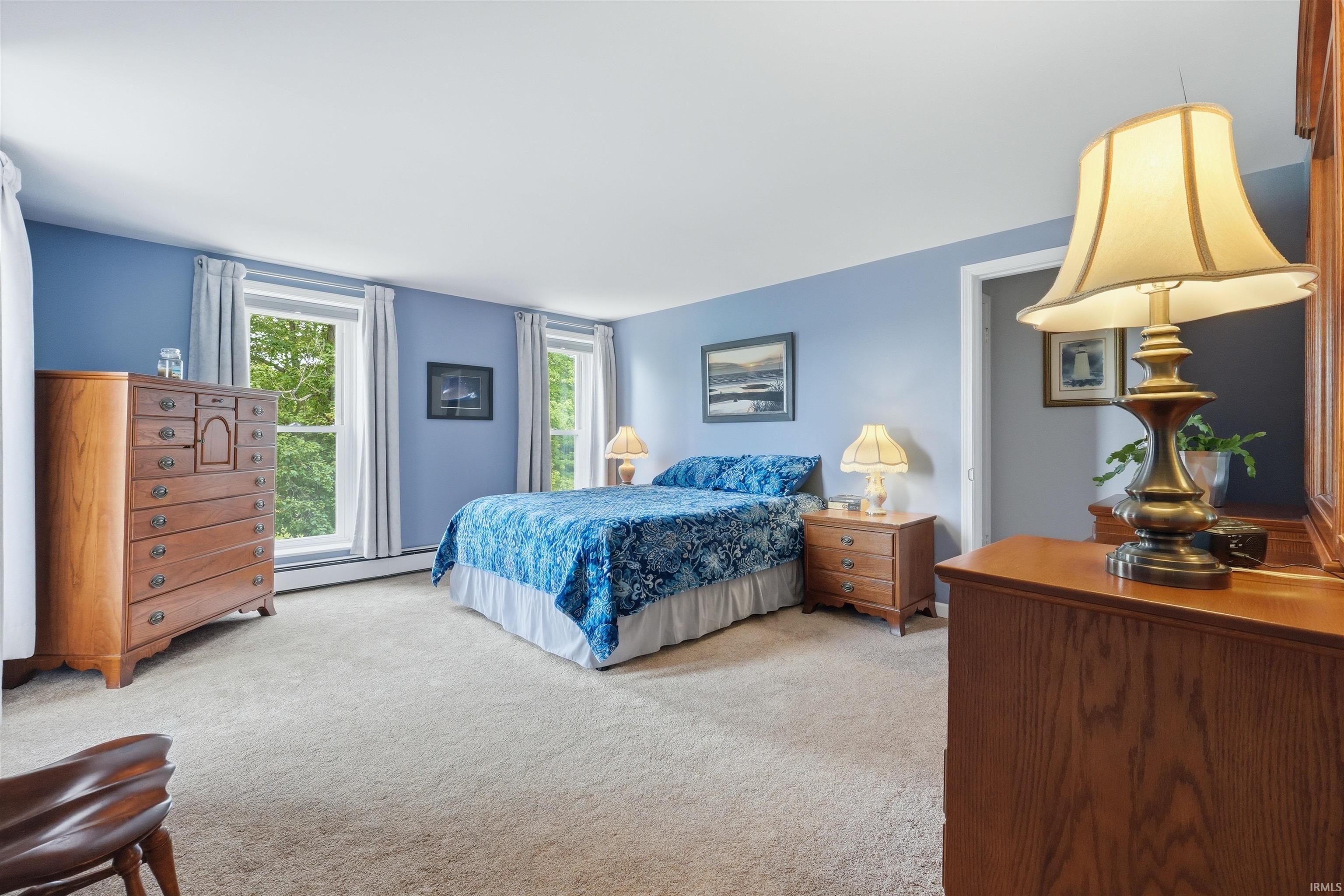 Carpeted bedroom with light blue walls and multiple large windows