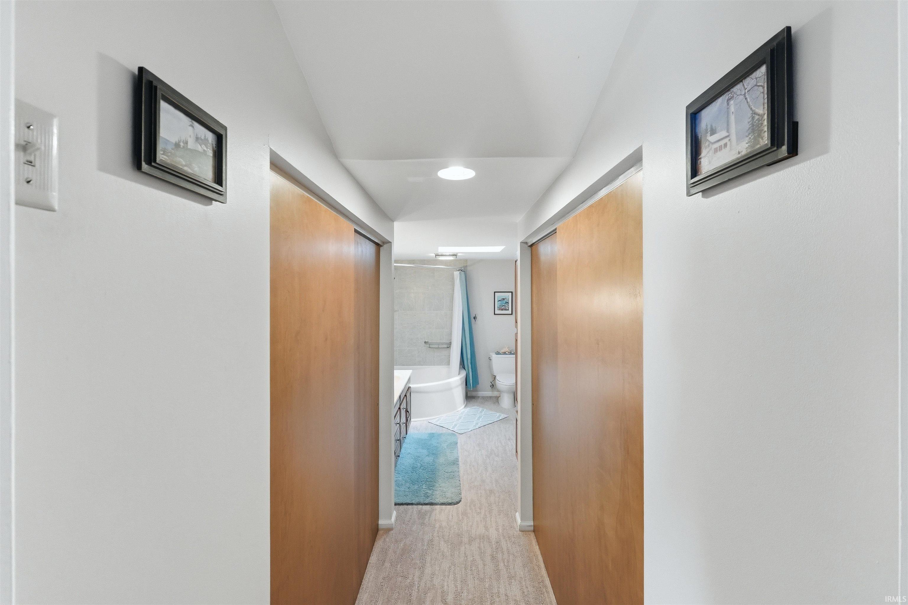Hallway featuring wood-finish sliding doors, recessed lighting, and light-toned flooring