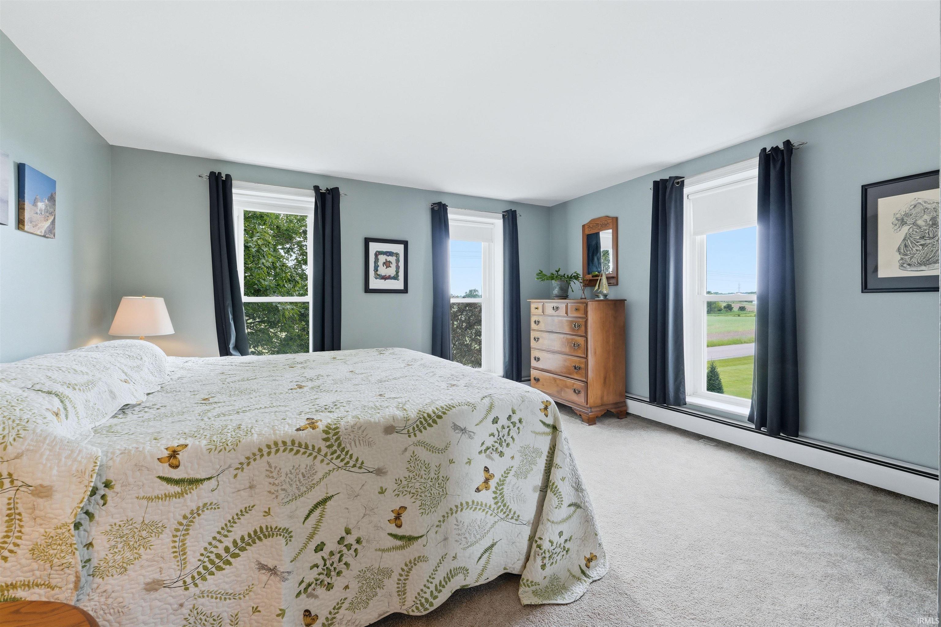 Light blue painted walls with white trim, carpeting, and multiple windows offering expansive outdoor views