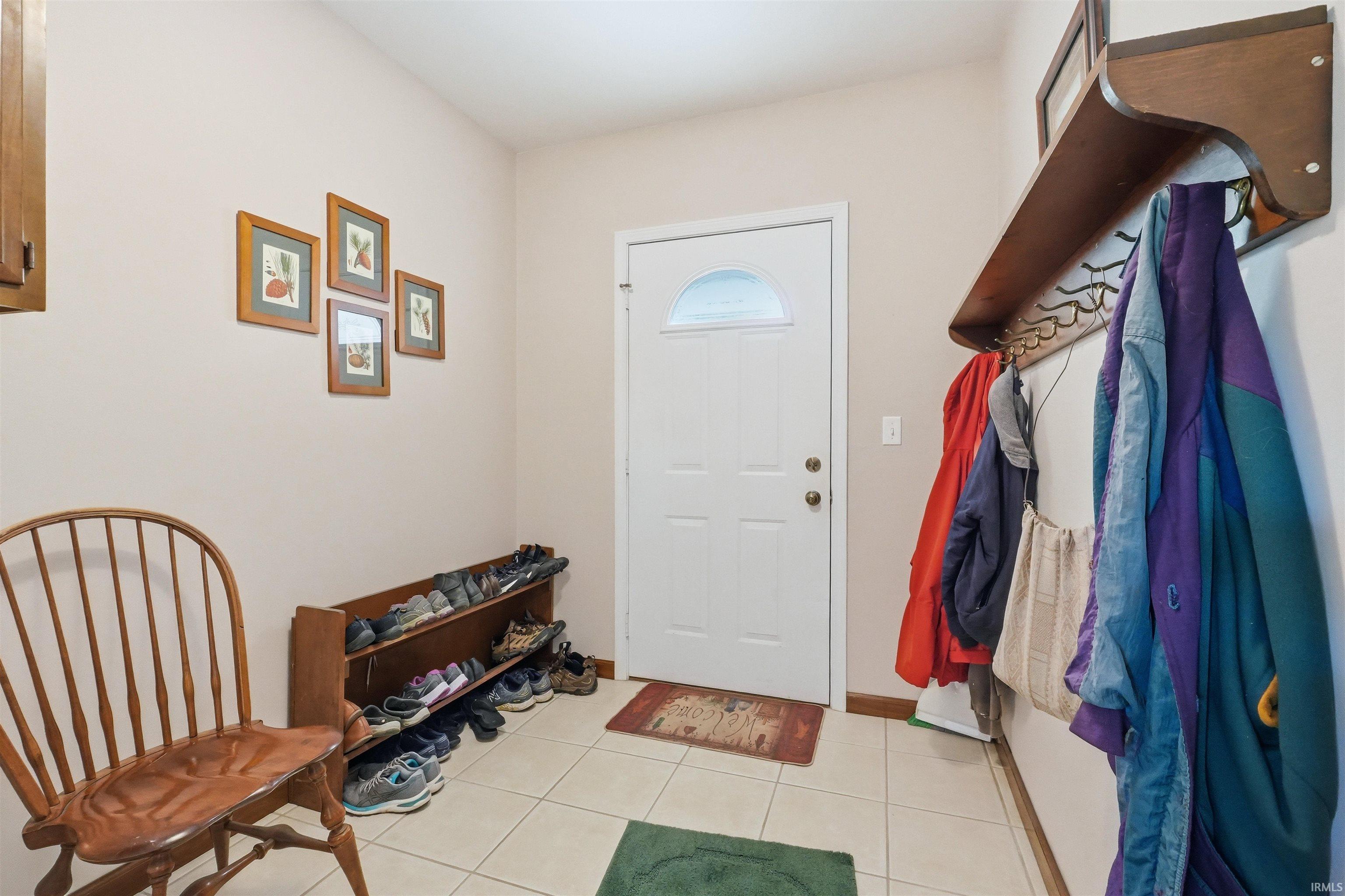 Entryway featuring a white paneled door with an arched window, light neutral wall paint, and square tile flooring