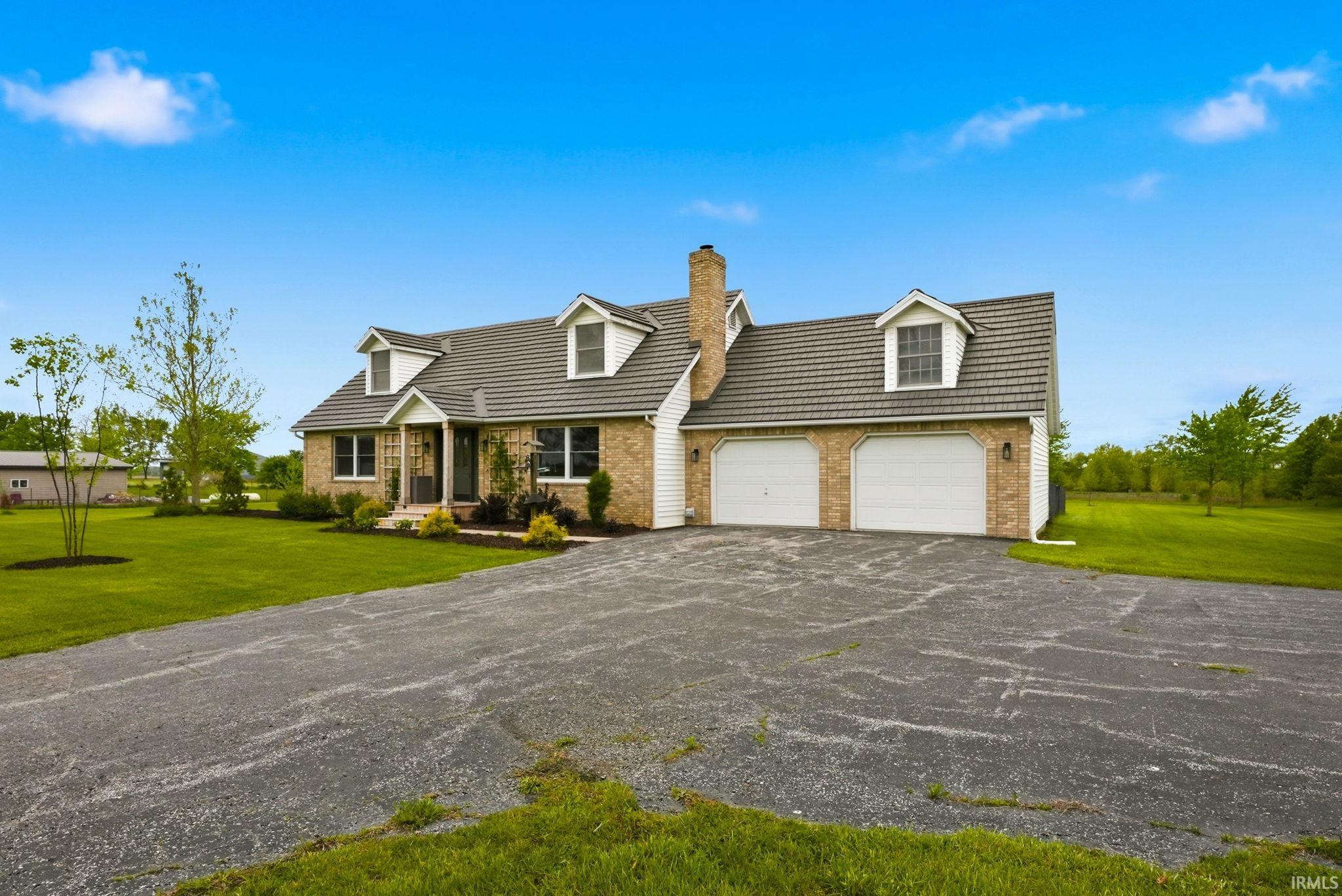 Brick-front residence featuring a two-car garage, dormer windows, and a prominent chimney