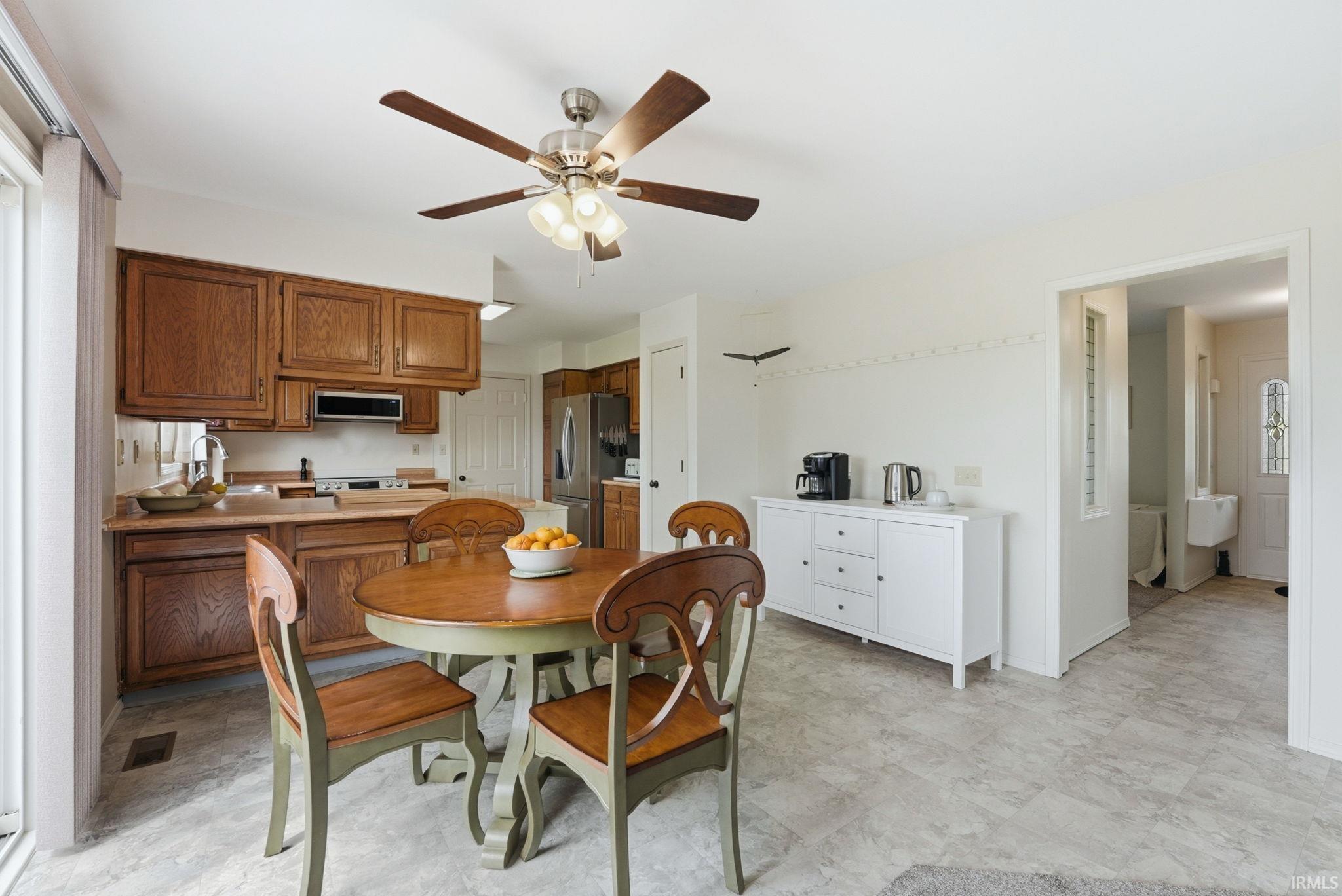 Kitchen and dining area featuring wood cabinetry, stainless steel refrigerator, and a ceiling fan with light fixture
