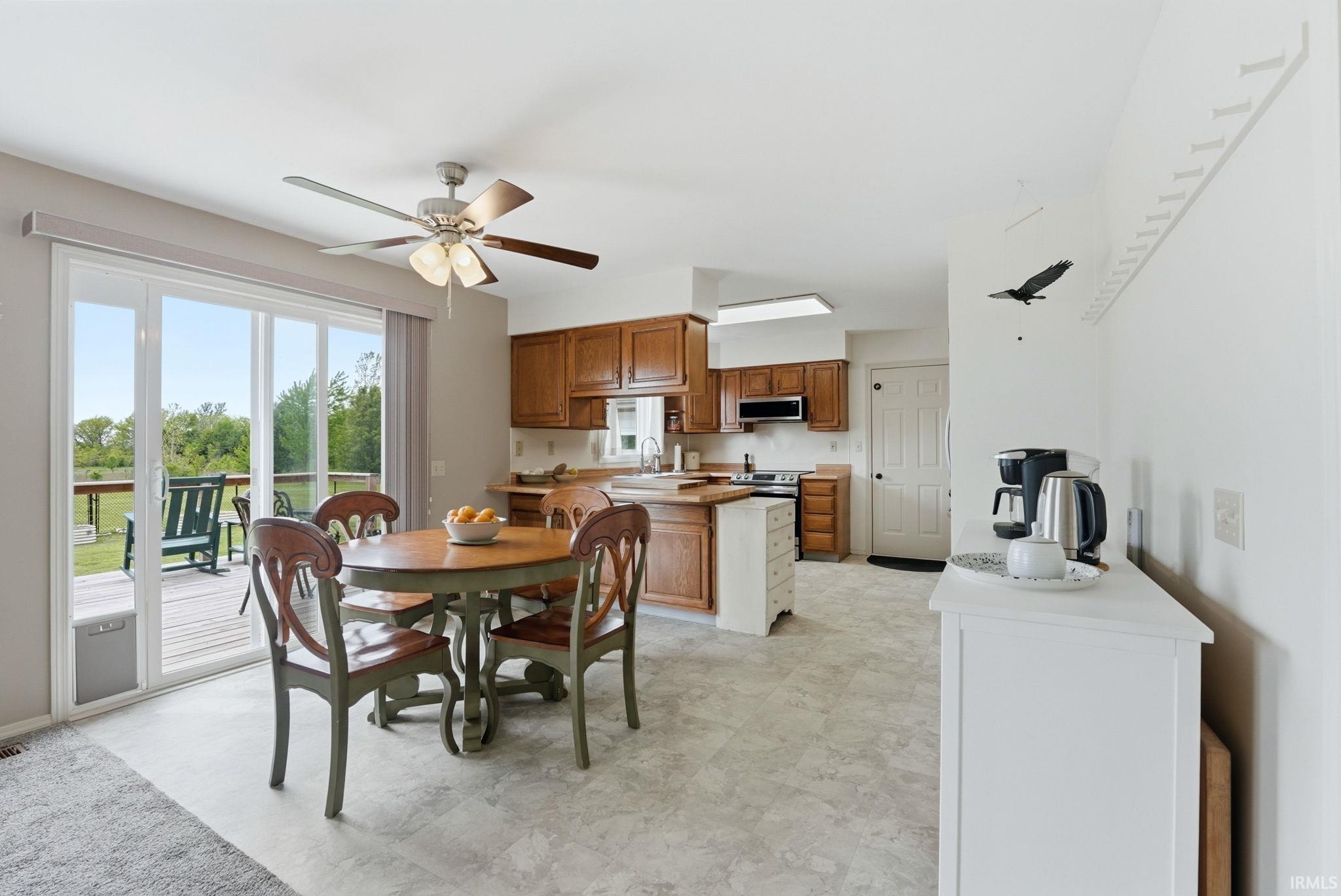 Open-concept kitchen and dining area featuring wood cabinetry, a built-in oven, and a ceiling fan