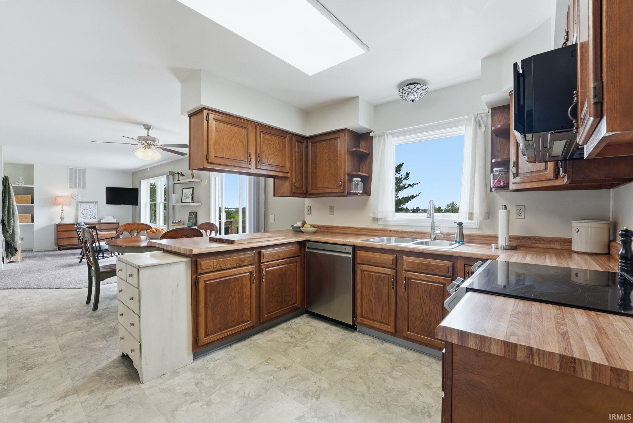 Kitchen featuring wood-finish cabinetry, butcher block style countertops, stainless steel dishwasher, and a built-in electric stovetop