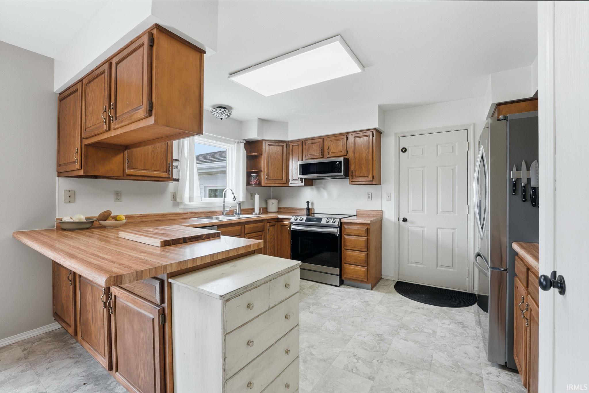 Kitchen featuring wood-finish cabinetry, stainless steel appliances, and wood-finish countertops