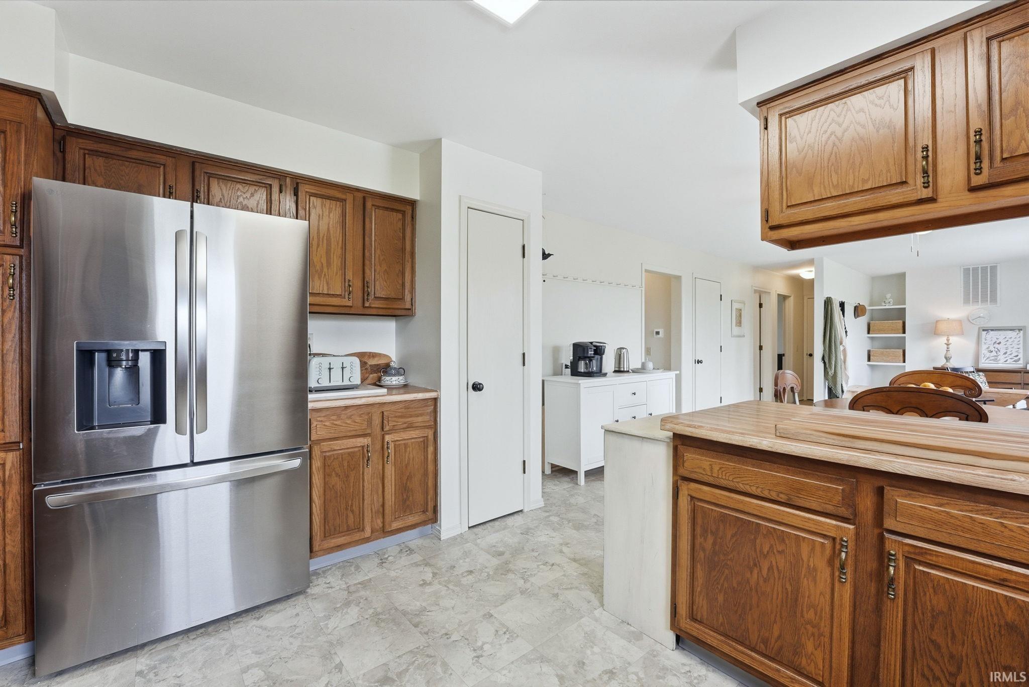 Kitchen featuring wood cabinetry, light-toned countertops, and a stainless steel refrigerator with an external ice and water dispenser