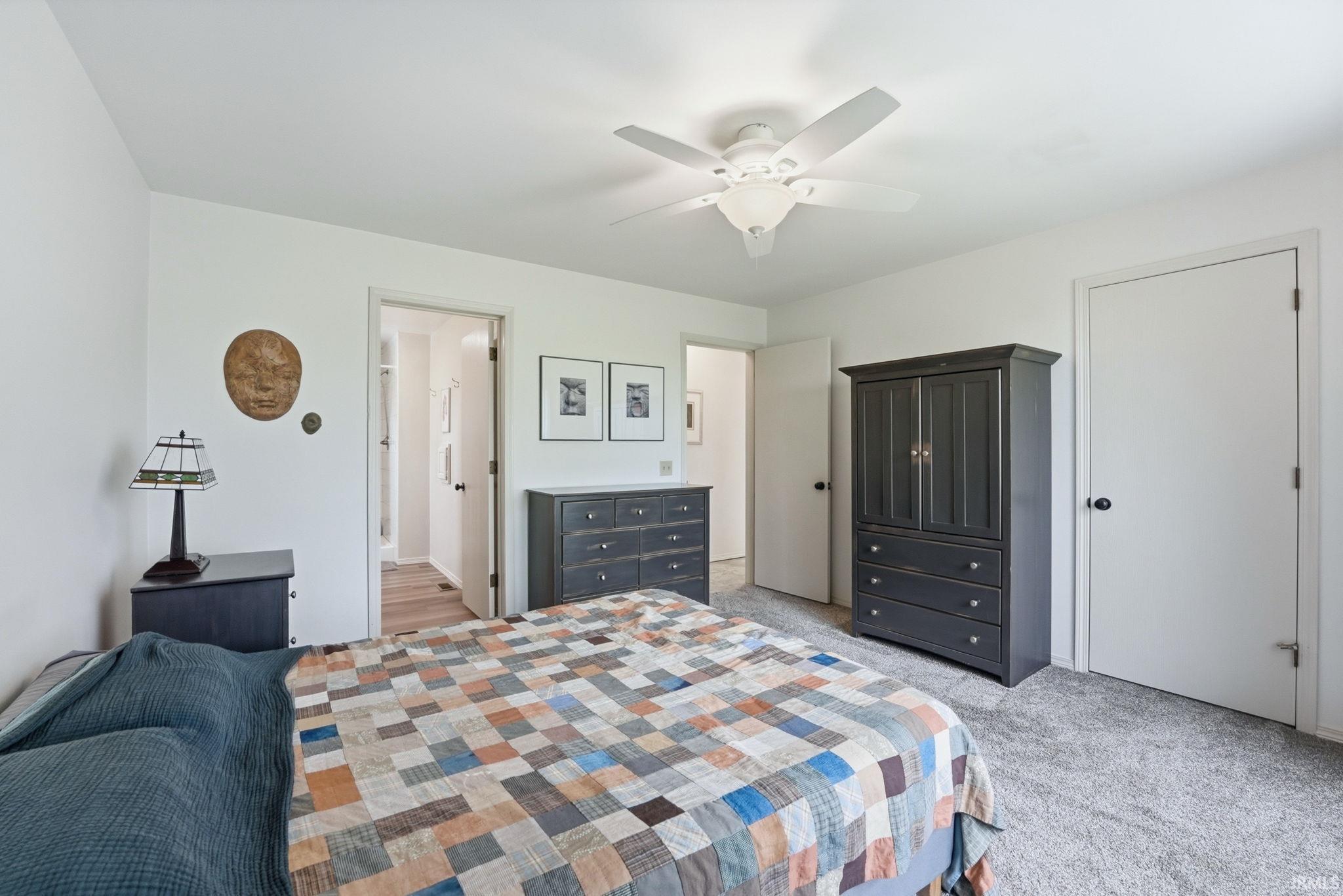 Carpeted bedroom featuring white walls and a ceiling fan with integrated lighting
