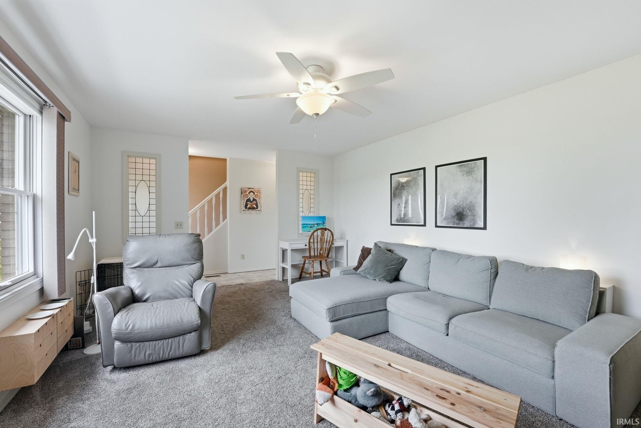 Bright living space featuring neutral wall tones and textured carpeting