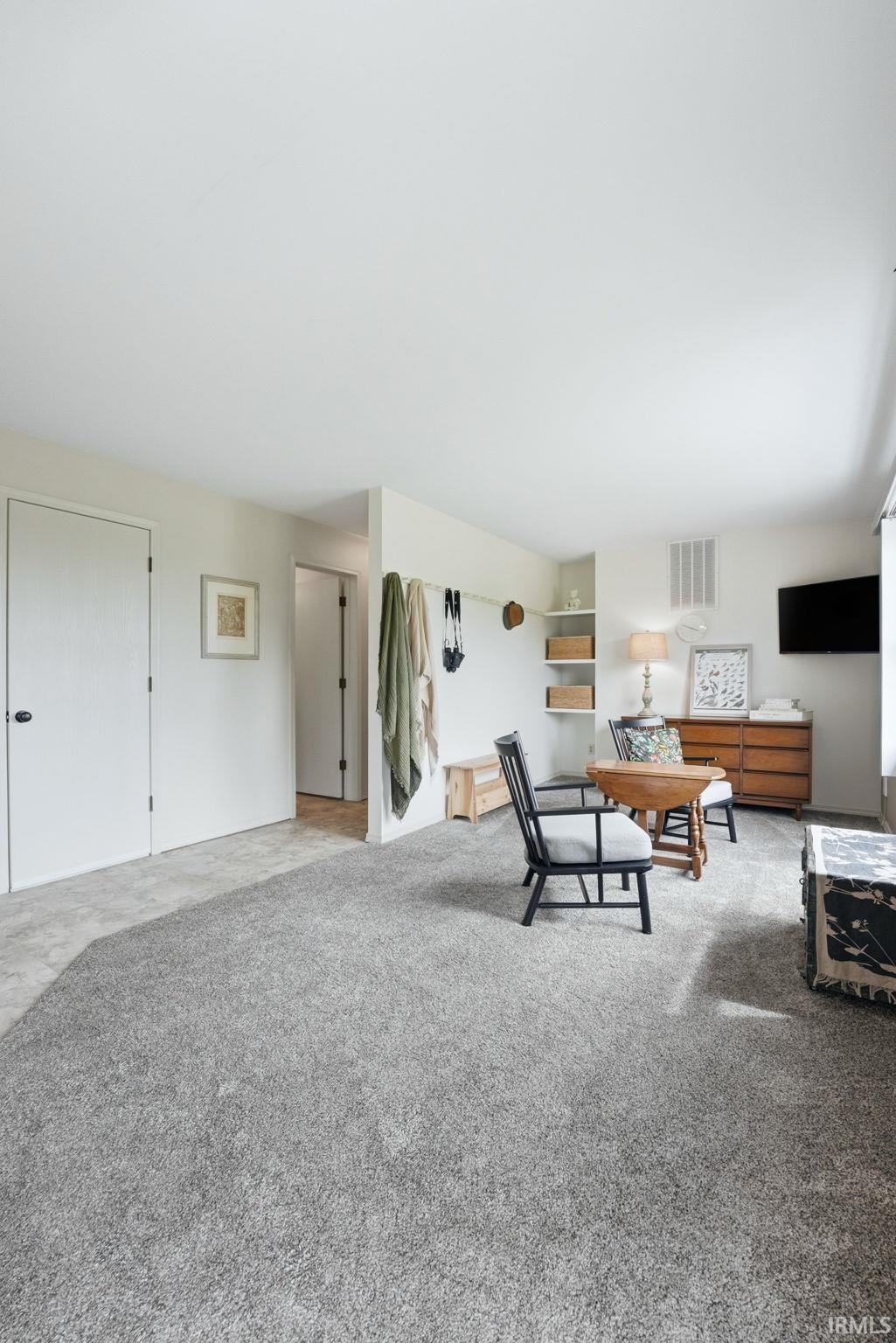 Wall-to-wall carpeting in a neutral tone, white walls, and built-in shelving