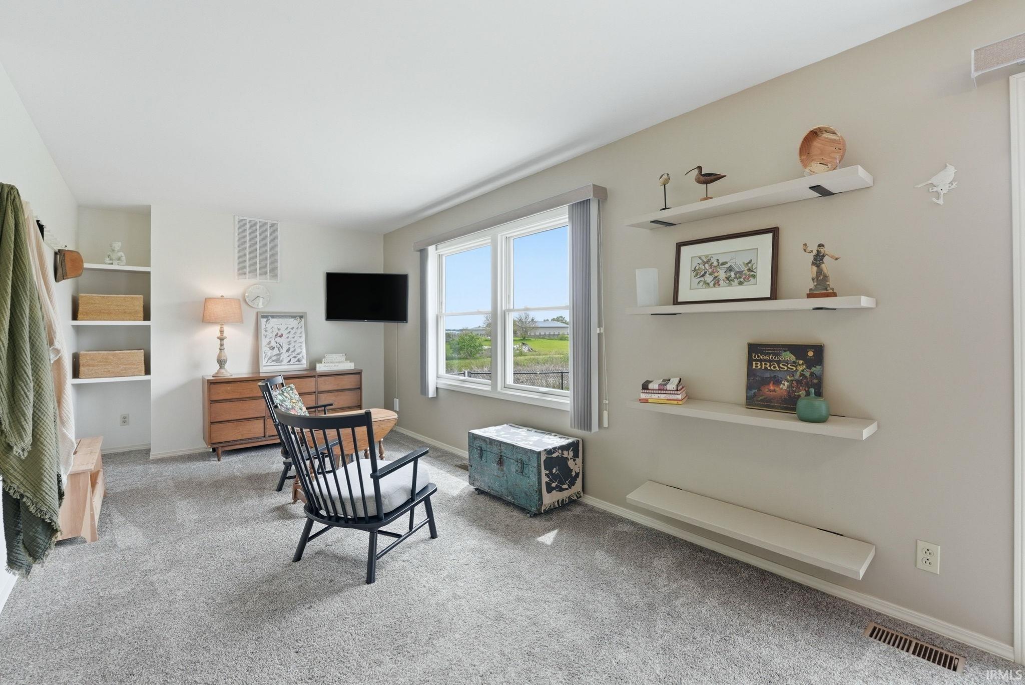 Living area featuring light gray wall paint, gray carpet flooring, and white trim