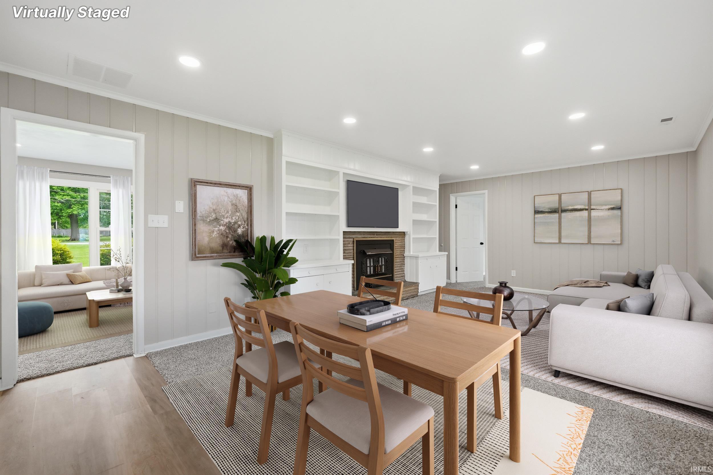 Spacious living area featuring neutral paneling, recessed lighting, built-in shelving, a fireplace with a brick surround, and wood-finish flooring