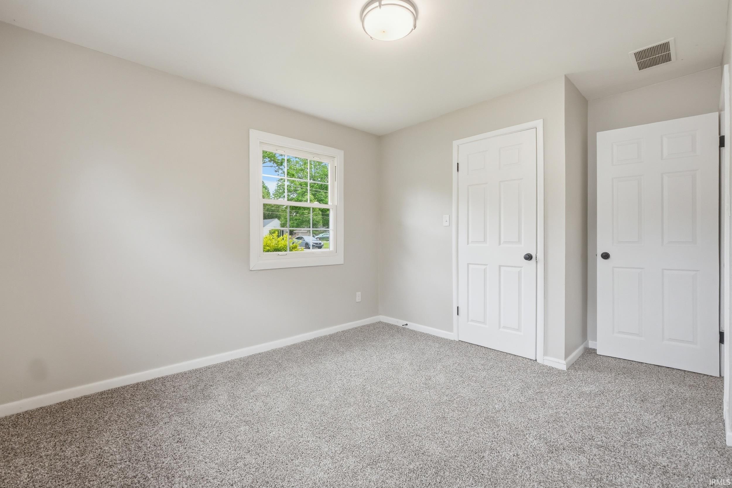 Room with light gray walls, gray carpeting, and white trim