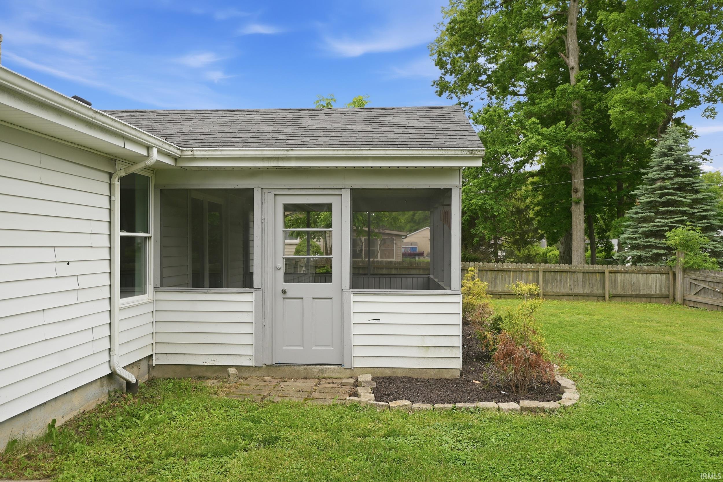 Exterior screened porch featuring a light gray door, white siding, and a shingle roof