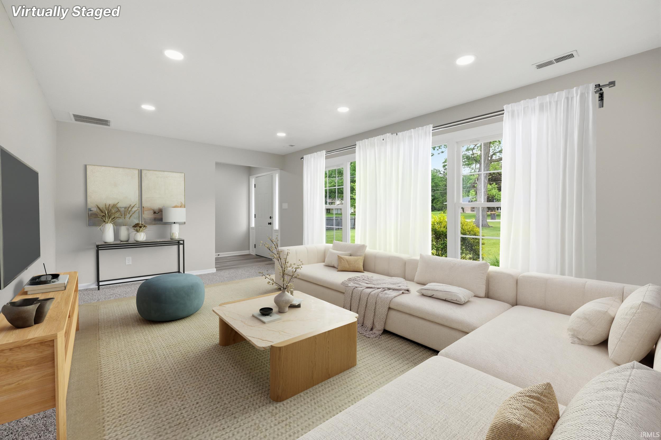 Spacious living area featuring expansive windows, recessed lighting, and wood-finish flooring