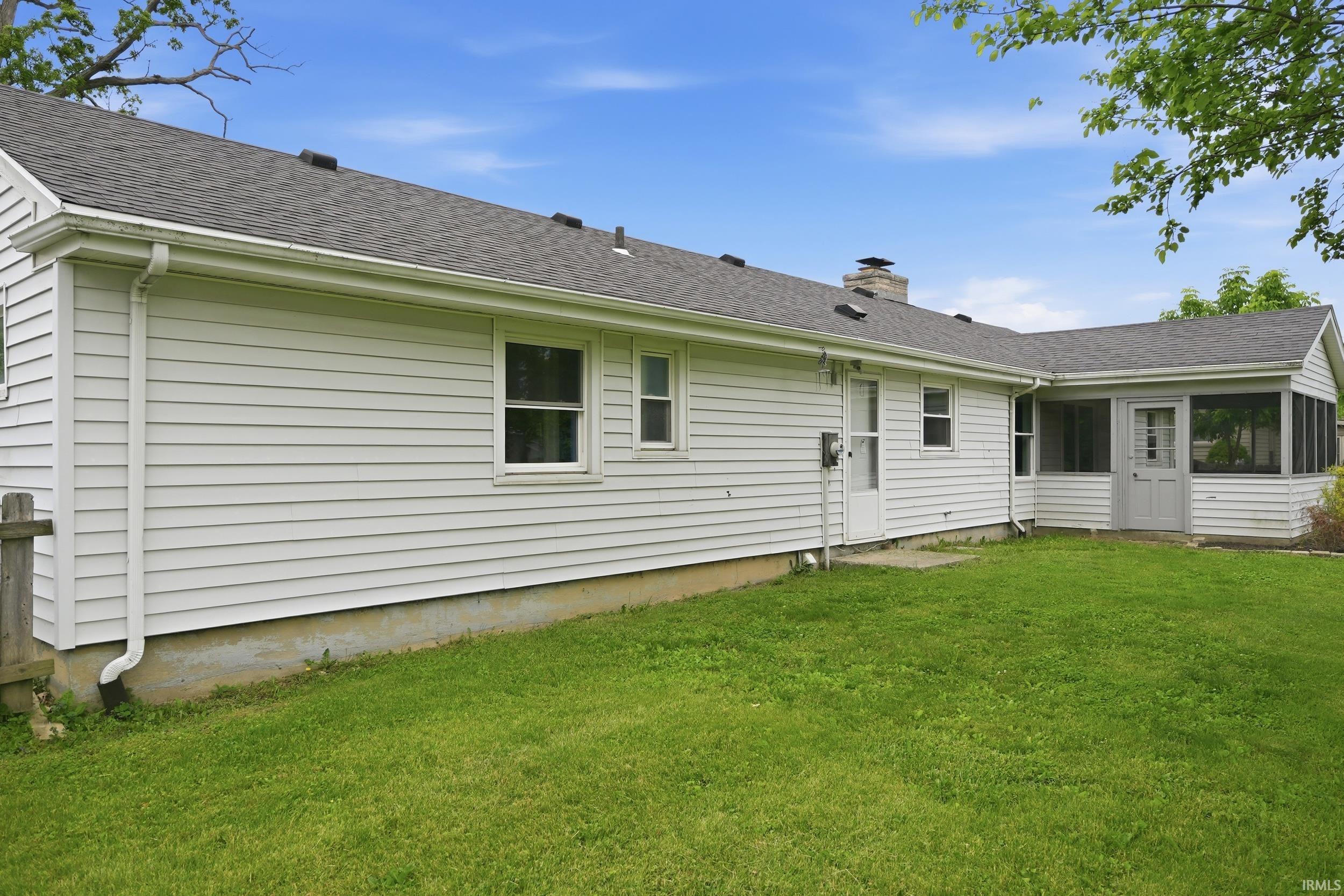 Rear exterior featuring white horizontal siding, a gray shingle roof, double-hung windows, and a screened-in porch with an exterior door