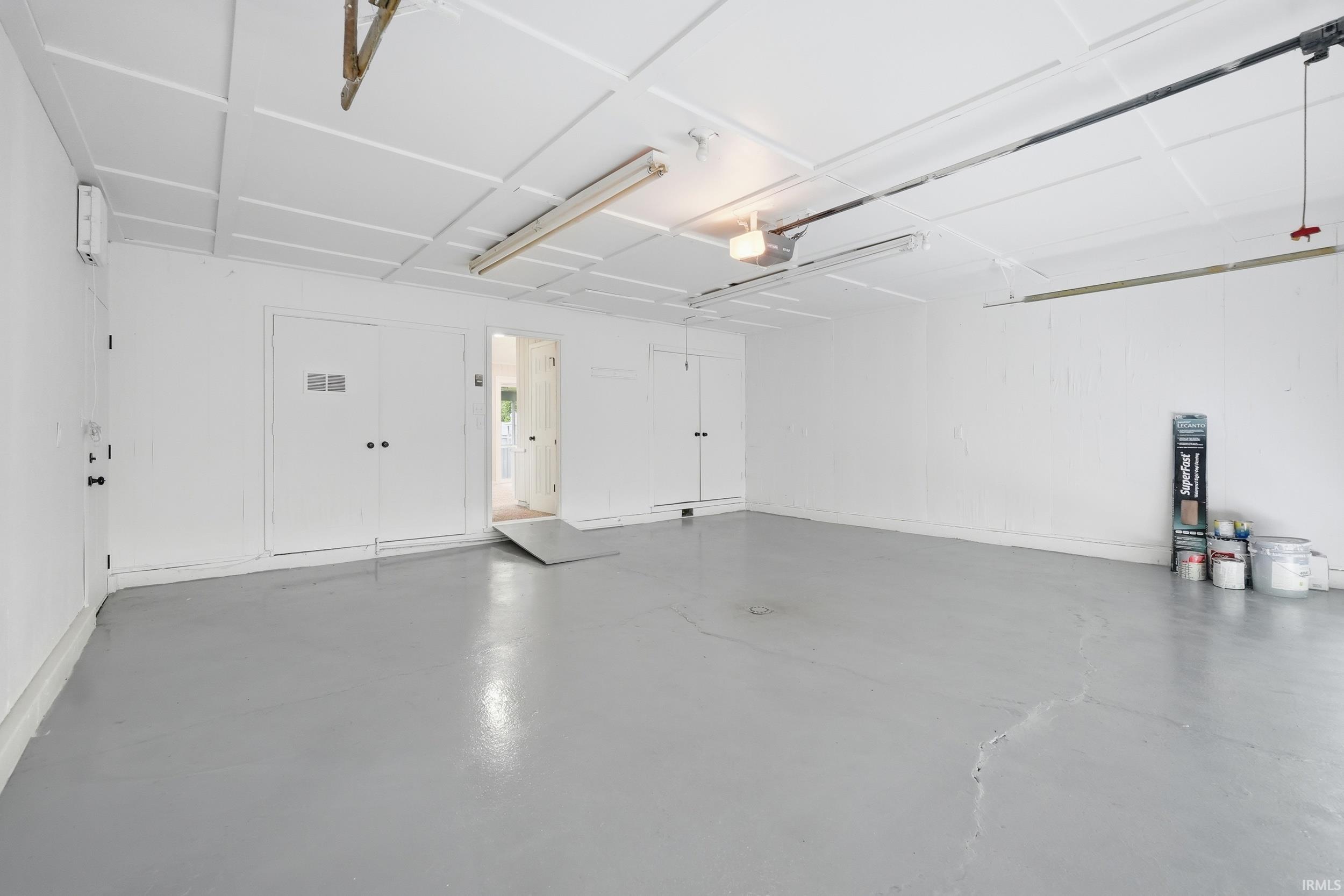 Spacious garage featuring a durable gray floor coating, white walls, and a paneled ceiling with overhead lighting