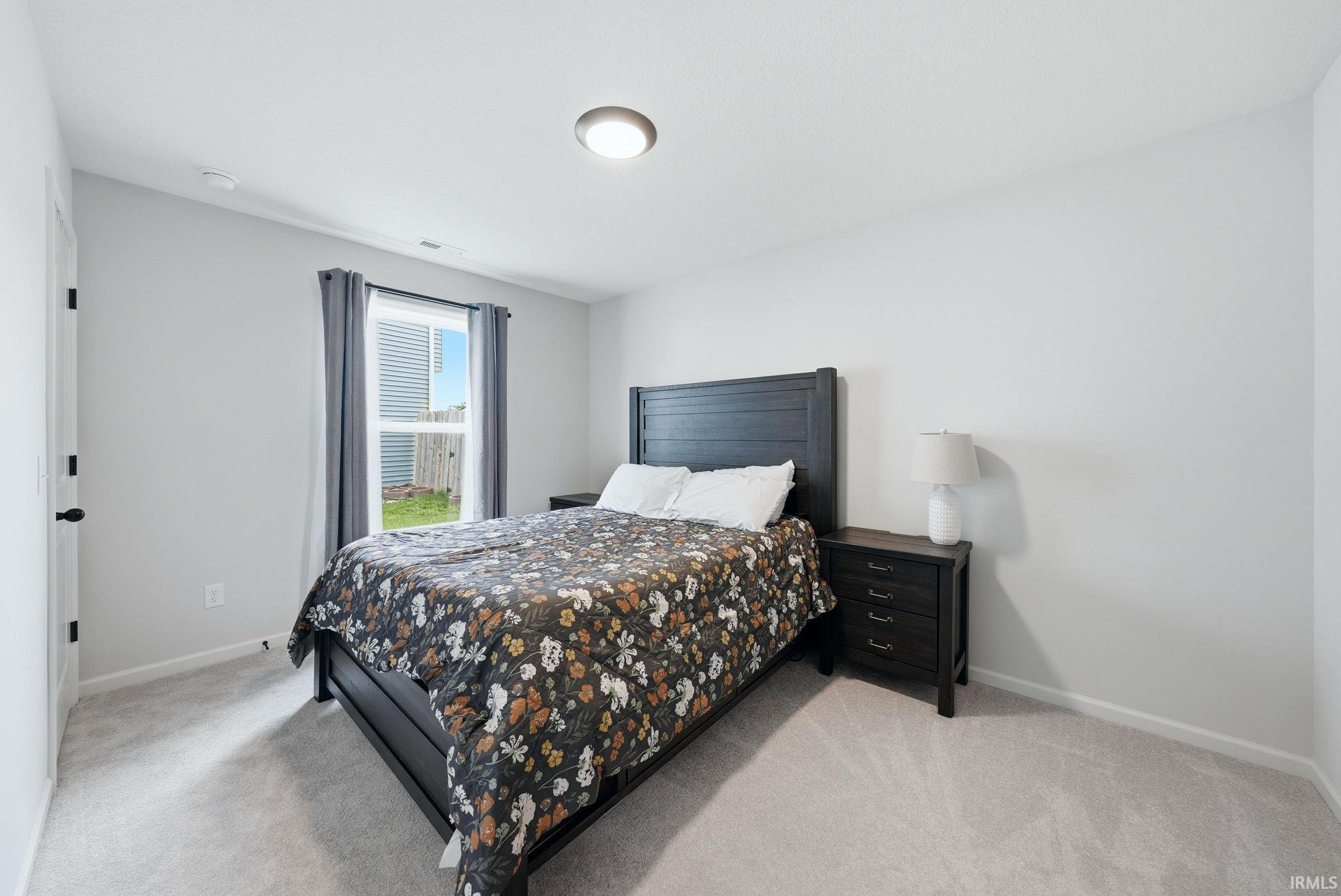 Carpeted room featuring light gray walls, a window with exterior views, and a flush mount ceiling light fixture