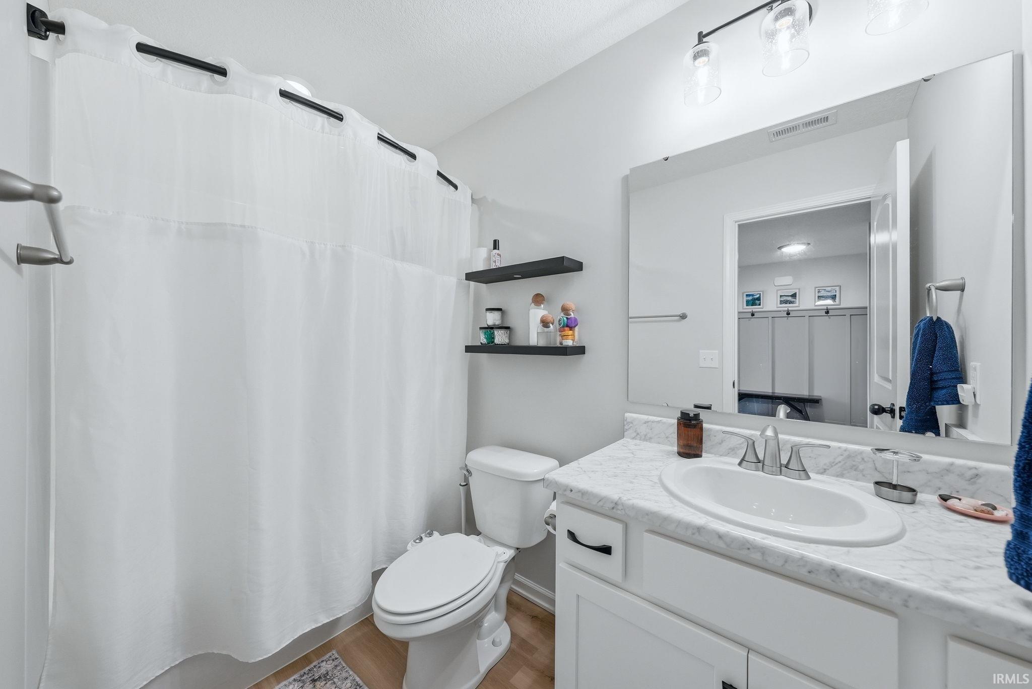 Bathroom featuring a white vanity with an undermount sink, a large wall-mounted mirror, and overhead vanity lighting