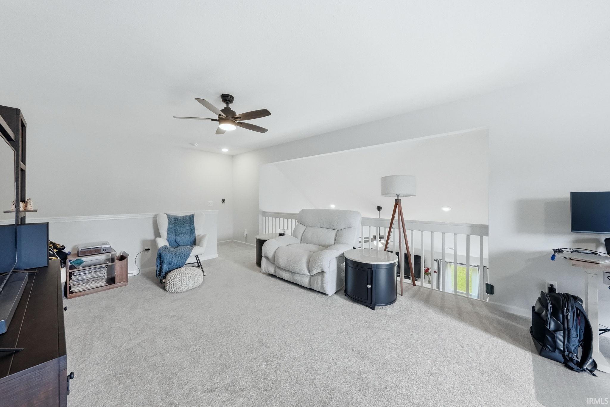 Carpeted loft space with a ceiling fan, white wall paint, recessed lighting, and a white railing overlooking the area below