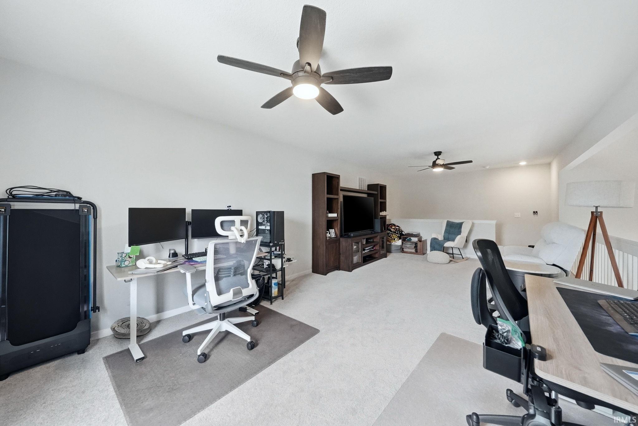 Spacious room featuring vaulted ceilings, light-colored carpeting, and contemporary ceiling fans