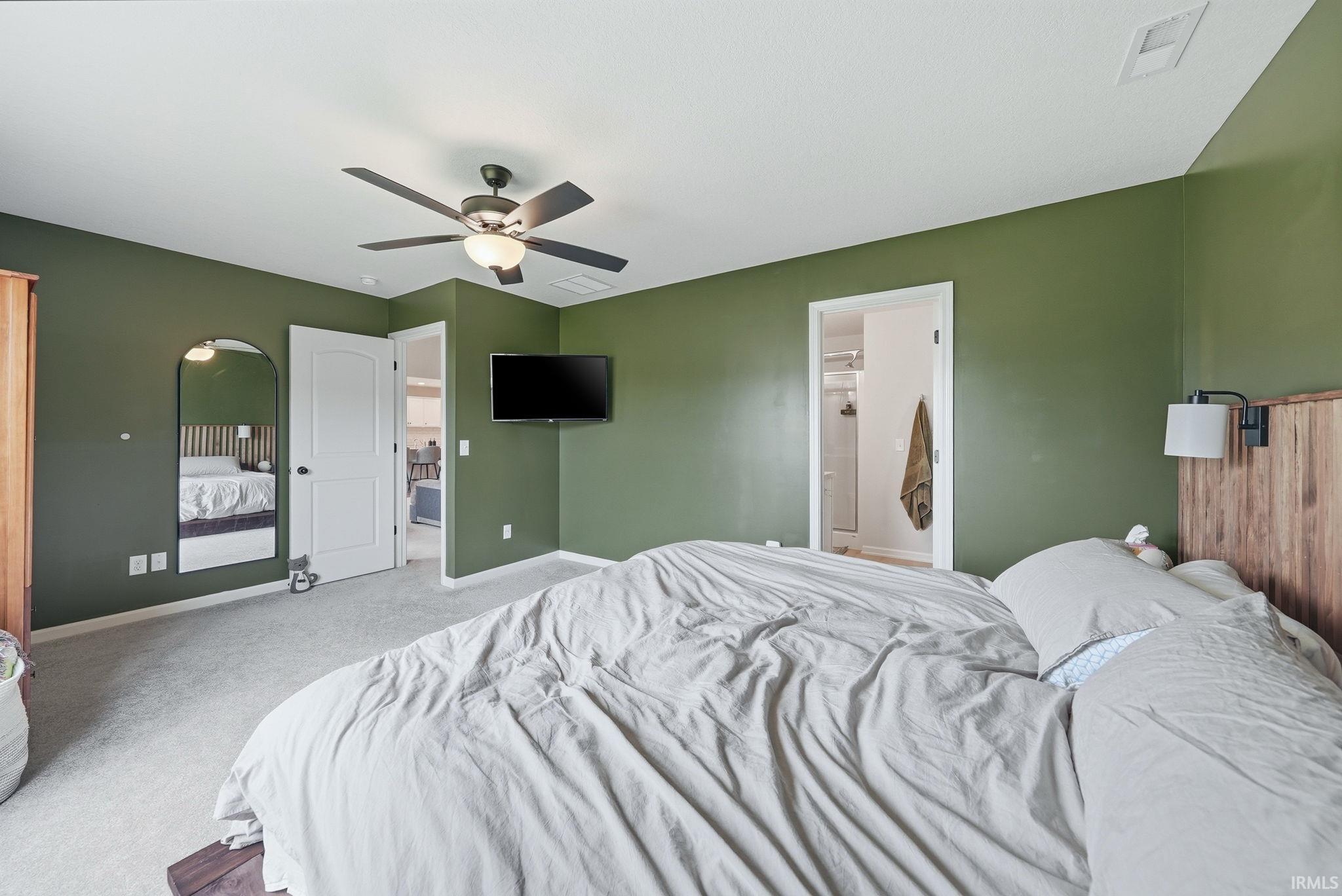 Spacious room featuring carpeting, a ceiling fan with integrated lighting, and multiple wall-mounted light fixtures