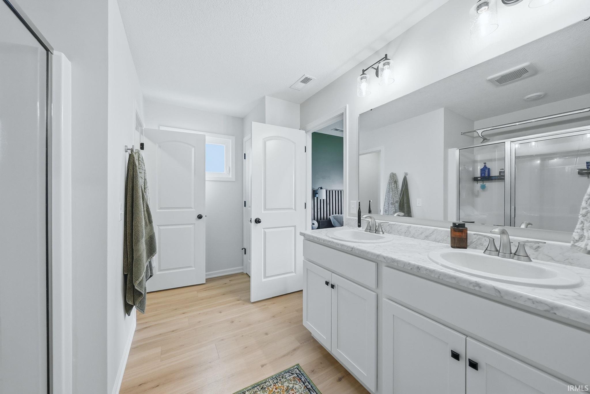 Dual vanity with white cabinetry and integrated sinks, complemented by a large wall-mounted mirror