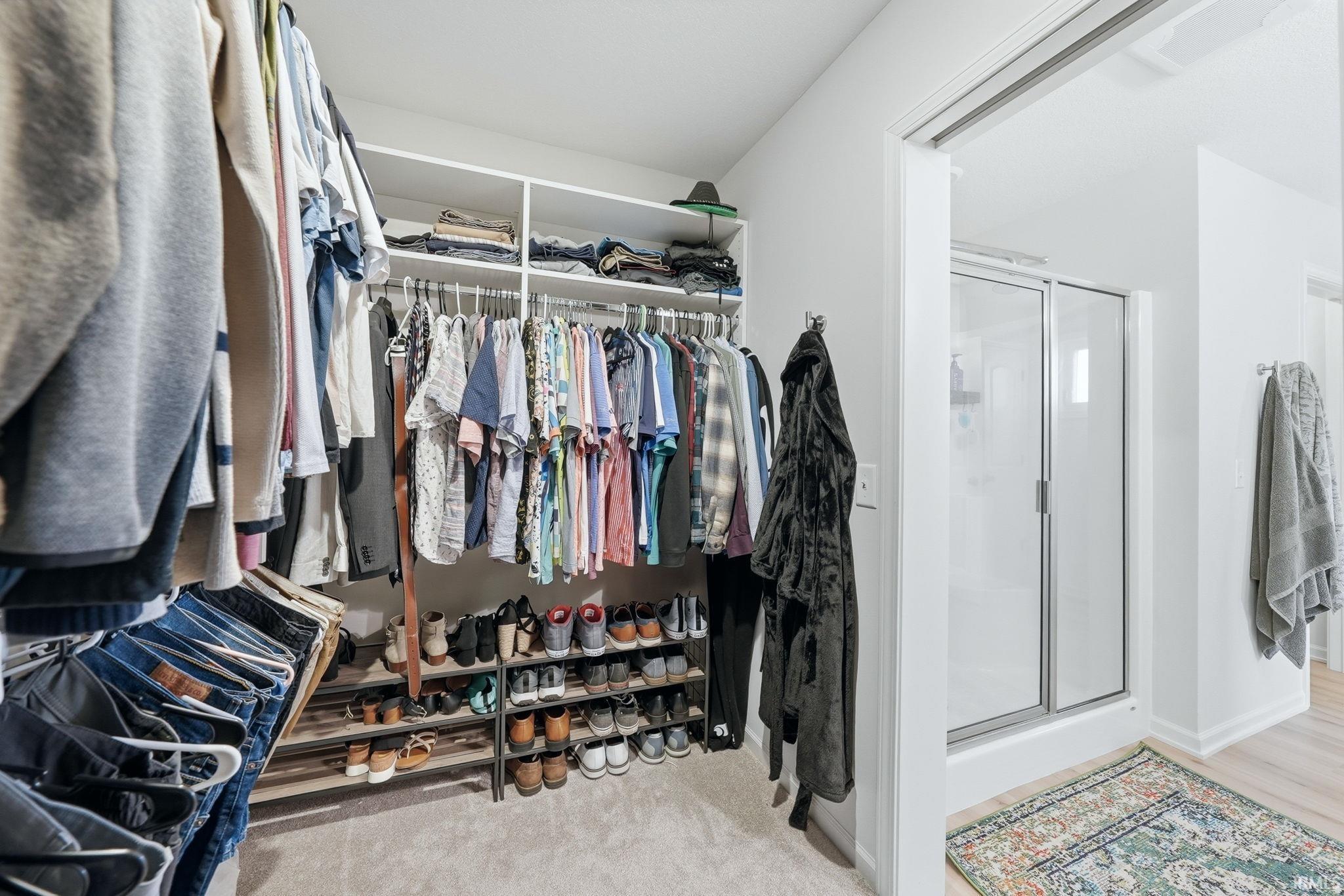 Walk-in closet with carpet flooring, built-in shelving, and multiple hanging rods