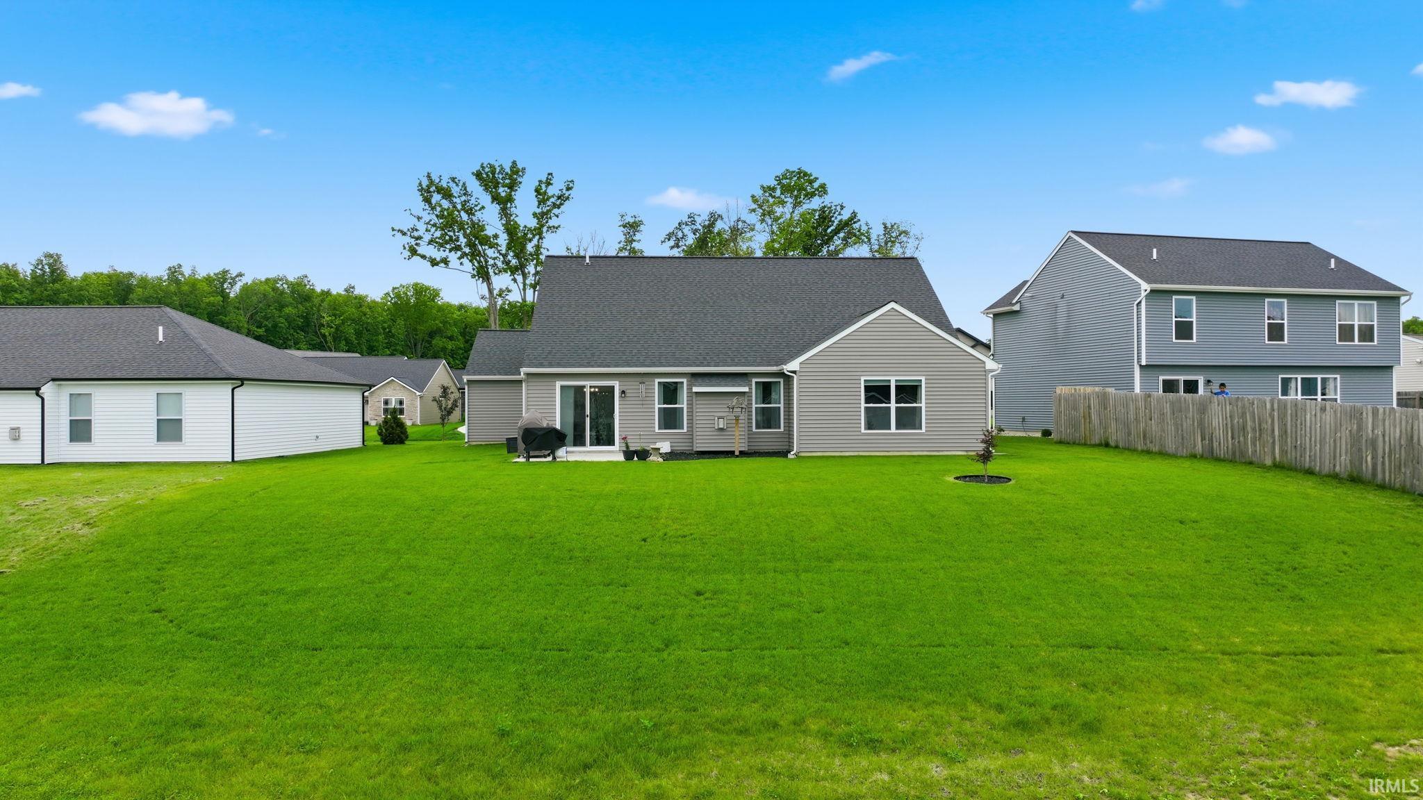 Expansive green lawn with a gray siding residence featuring a dark shingle roof