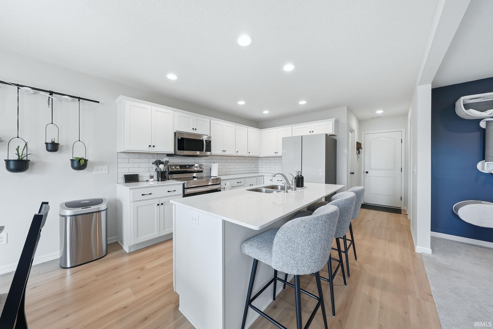 Modern kitchen featuring white cabinetry, stainless steel appliances, and a subway tile backsplash