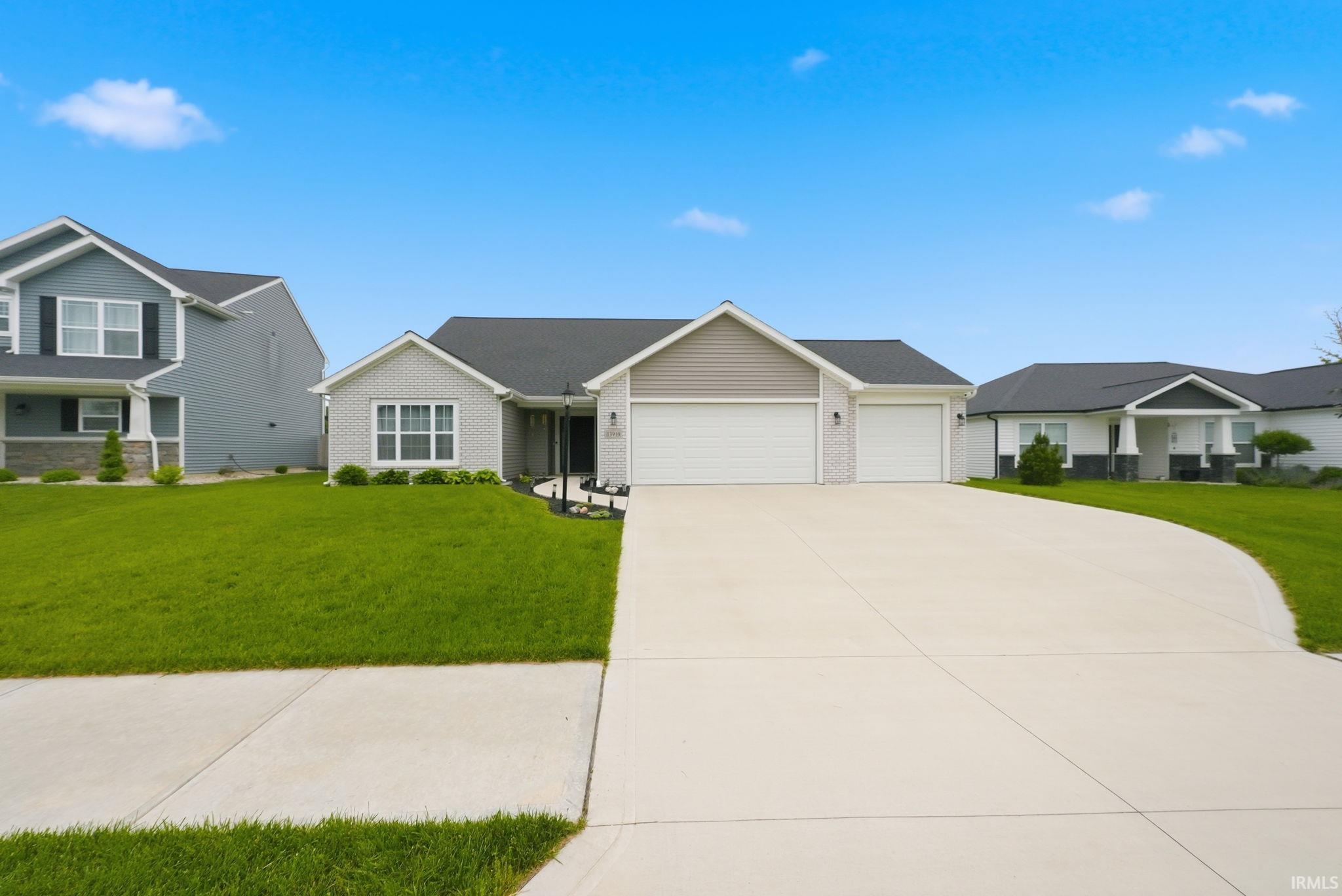 Ranch-style residence featuring a two-car garage, light brick facade, and gray siding accents