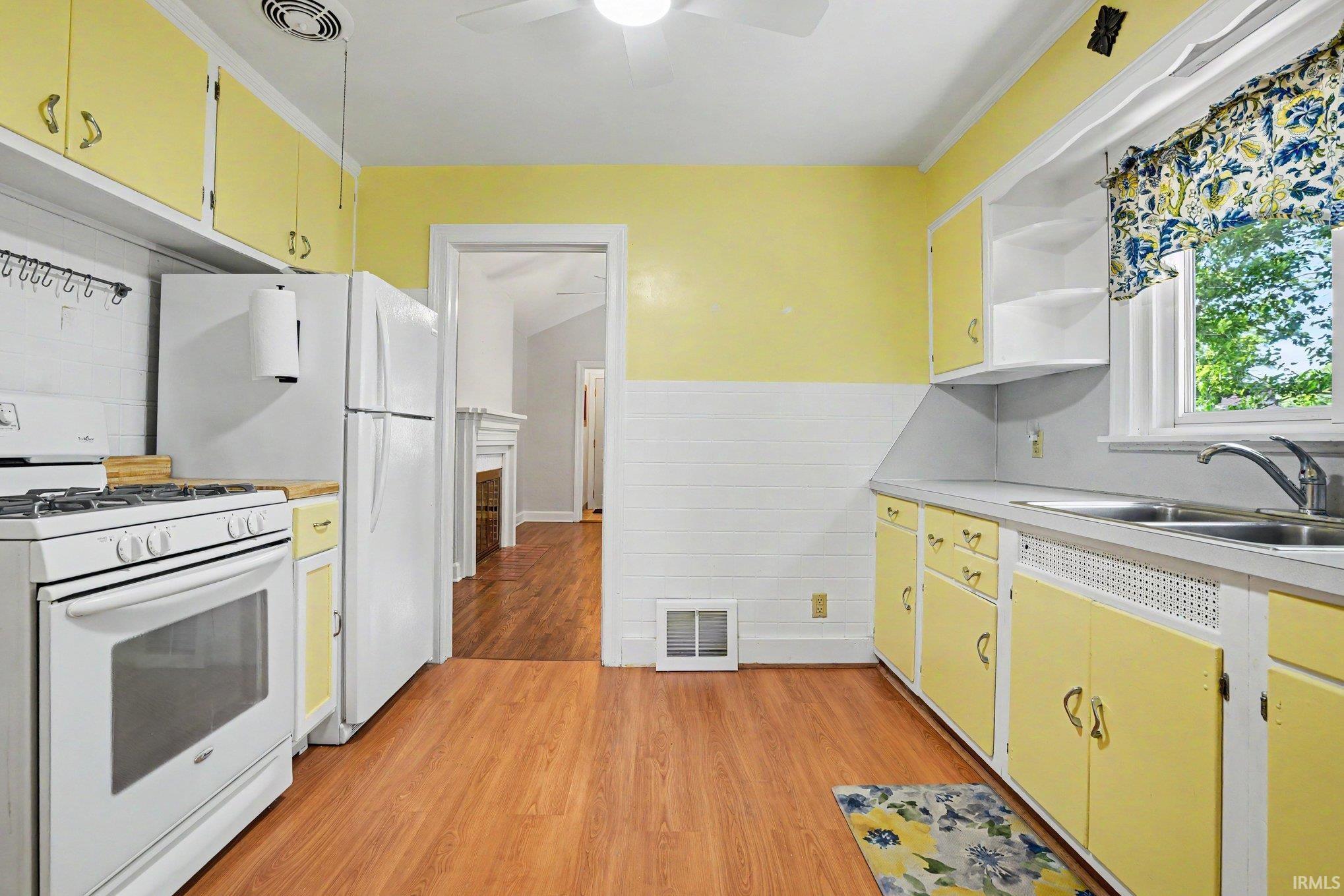 Kitchen featuring wood-finish flooring, yellow cabinetry, a double basin sink, and a window with natural light