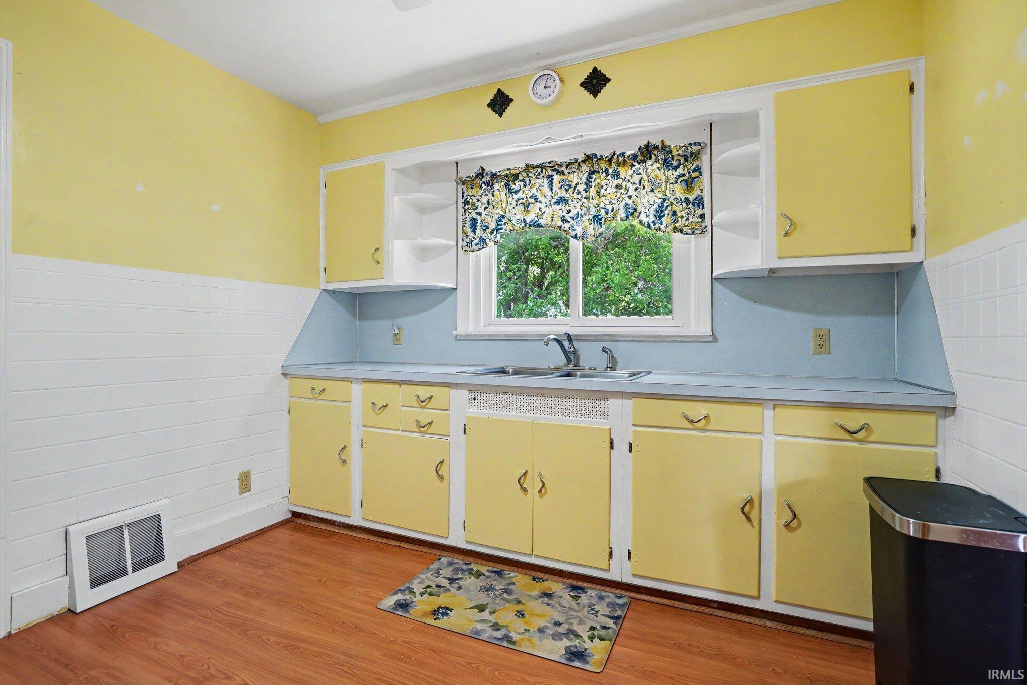 Kitchen featuring a window above the sink, yellow cabinetry, blue countertops, and wood-finish flooring