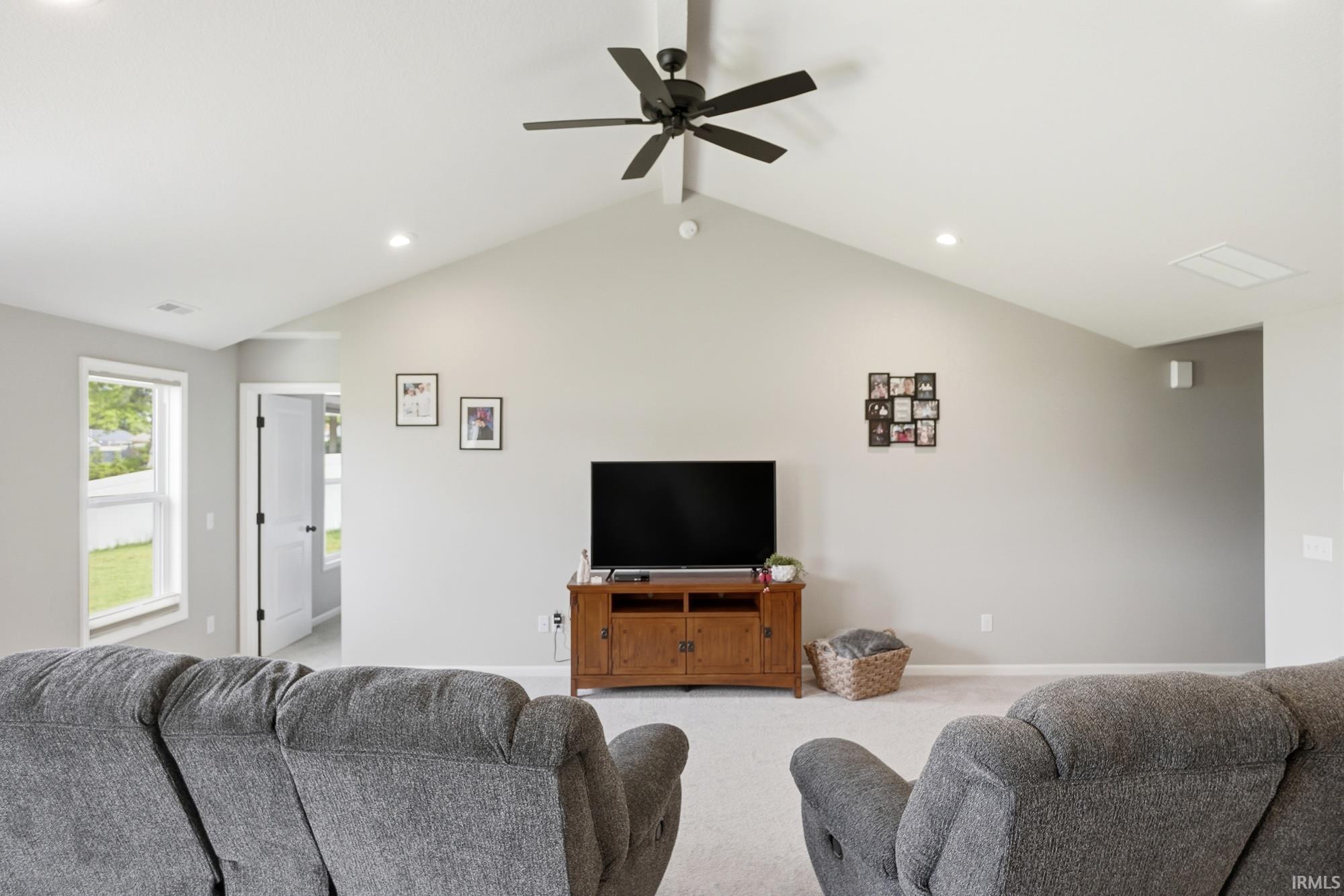 Vaulted ceiling living space featuring a ceiling fan, recessed lighting, and light-colored carpeting