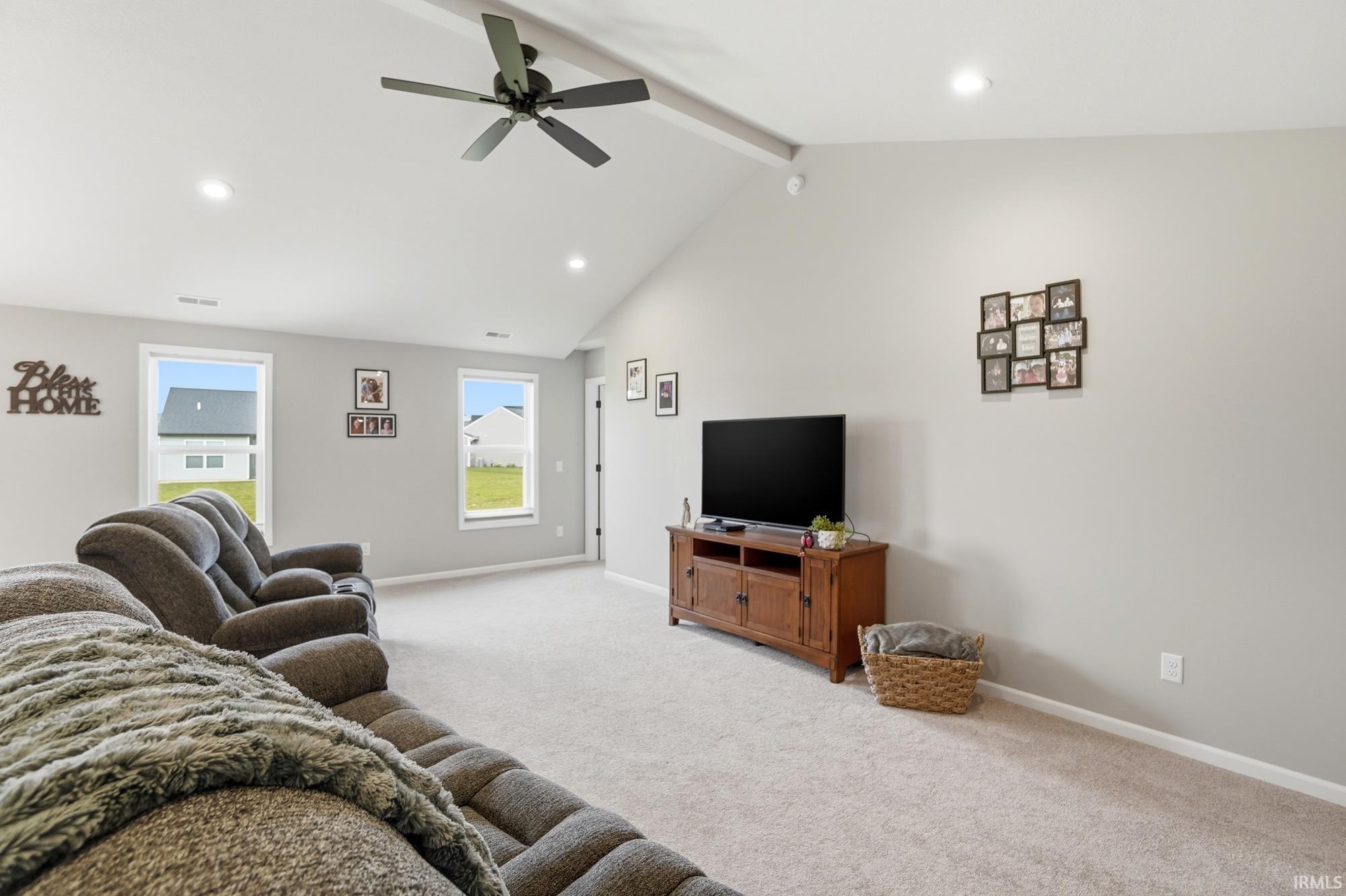 Spacious room featuring a vaulted ceiling with exposed beam, recessed lighting, and a ceiling fan