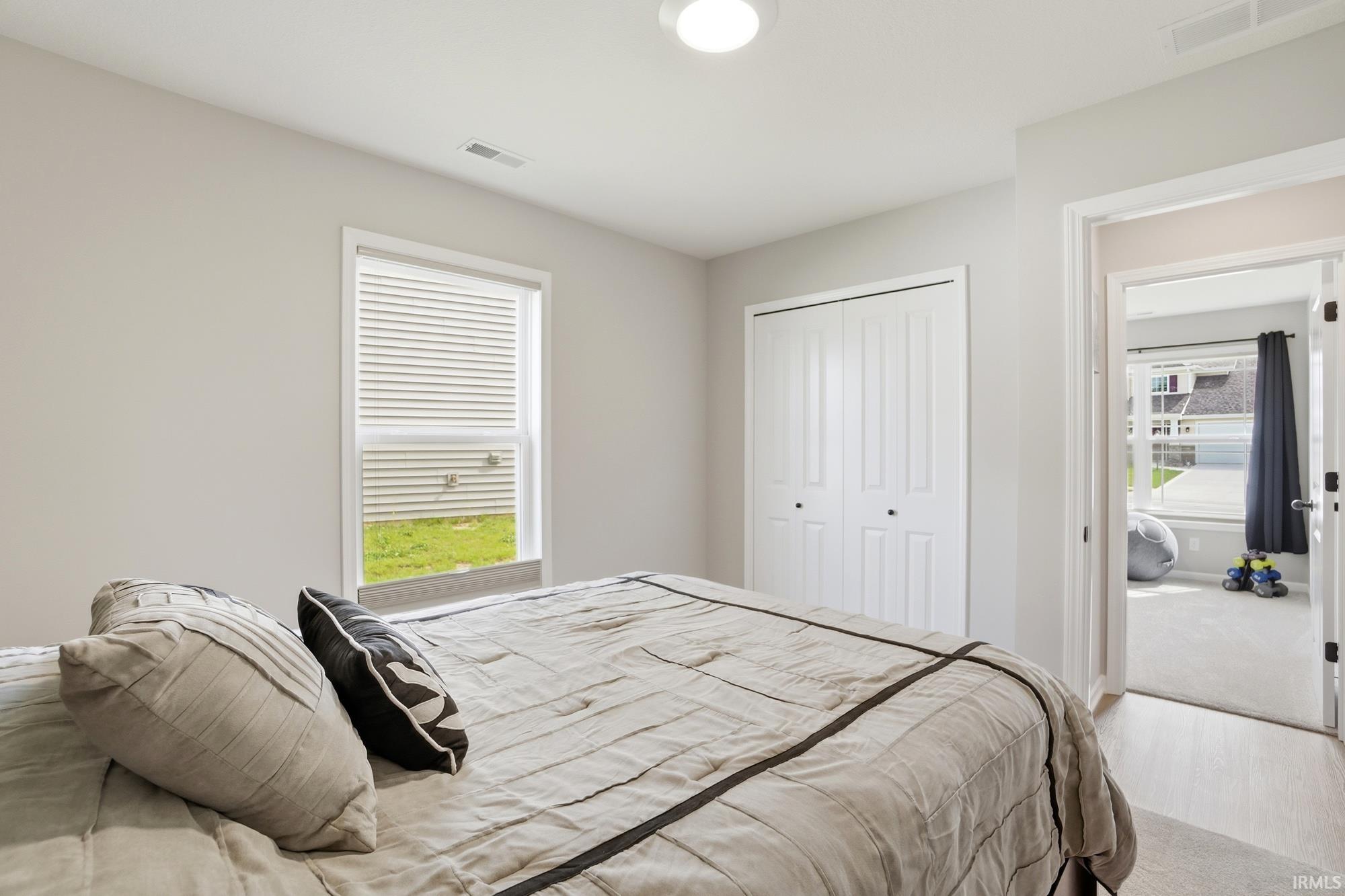 Bedroom with a window featuring horizontal blinds, a ceiling-mounted light fixture, and a bi-fold closet