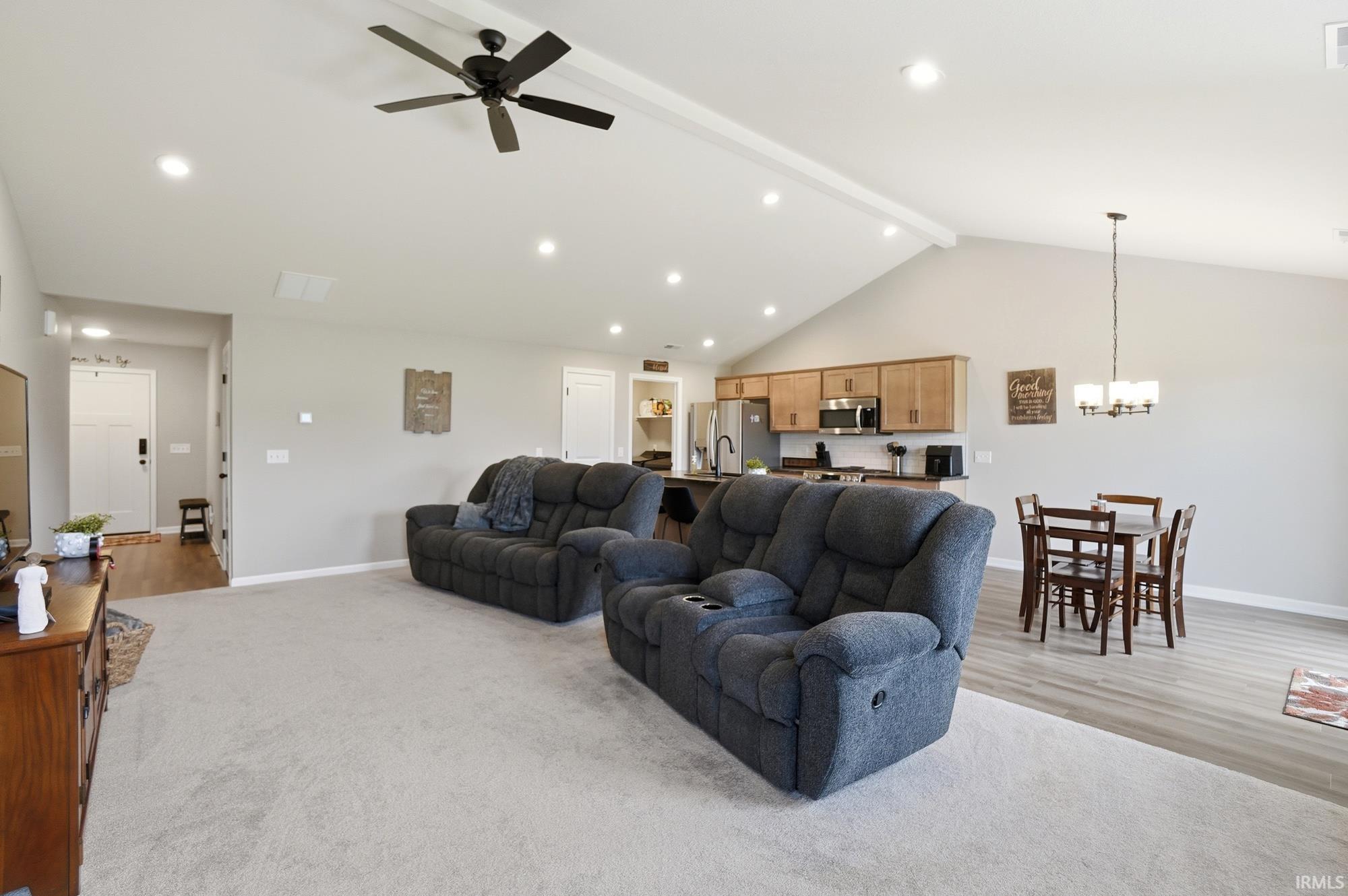 Spacious living area featuring a vaulted ceiling with exposed beam, recessed lighting, and a contemporary ceiling fan