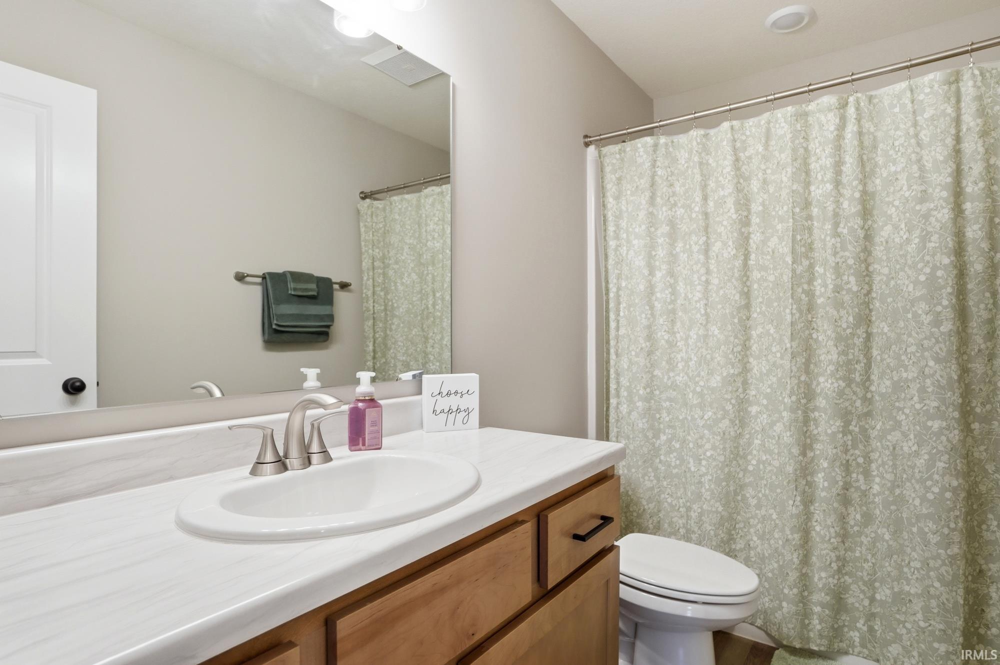Bathroom featuring a light wood-finish vanity with an integrated sink, white countertop, and brushed nickel faucet