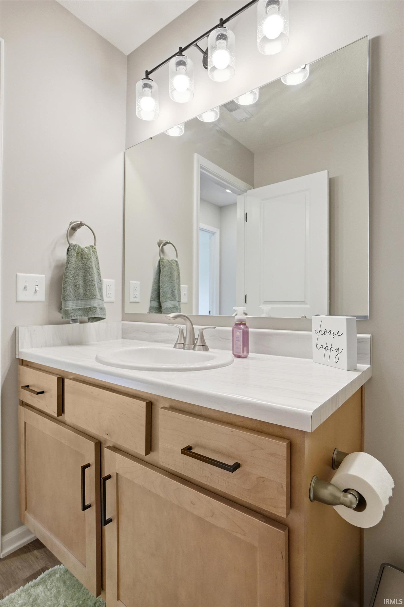 Contemporary vanity with light wood-finish cabinetry, a single basin sink, and brushed nickel faucet