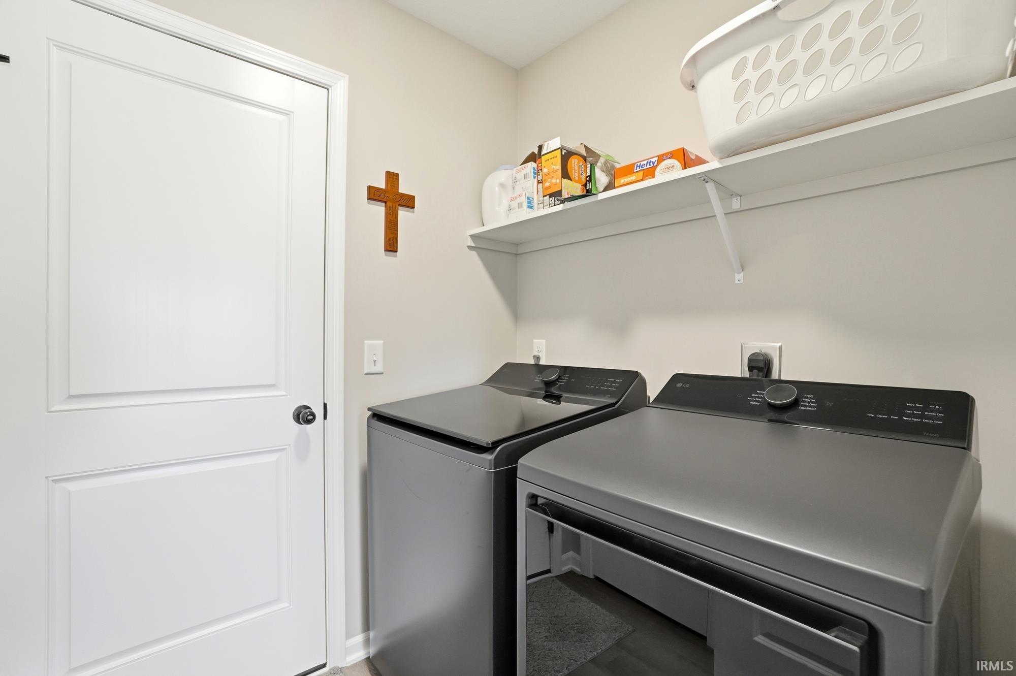 Dedicated laundry area featuring a white door, light-toned walls, and wood-finish flooring
