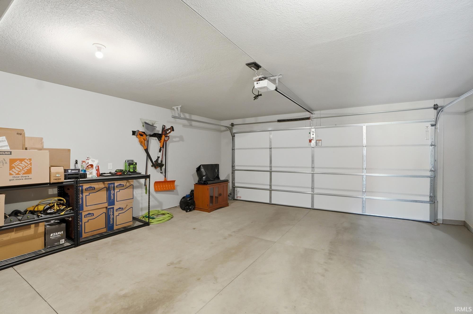 Spacious garage featuring a concrete floor, white interior walls, and an automatic garage door opener