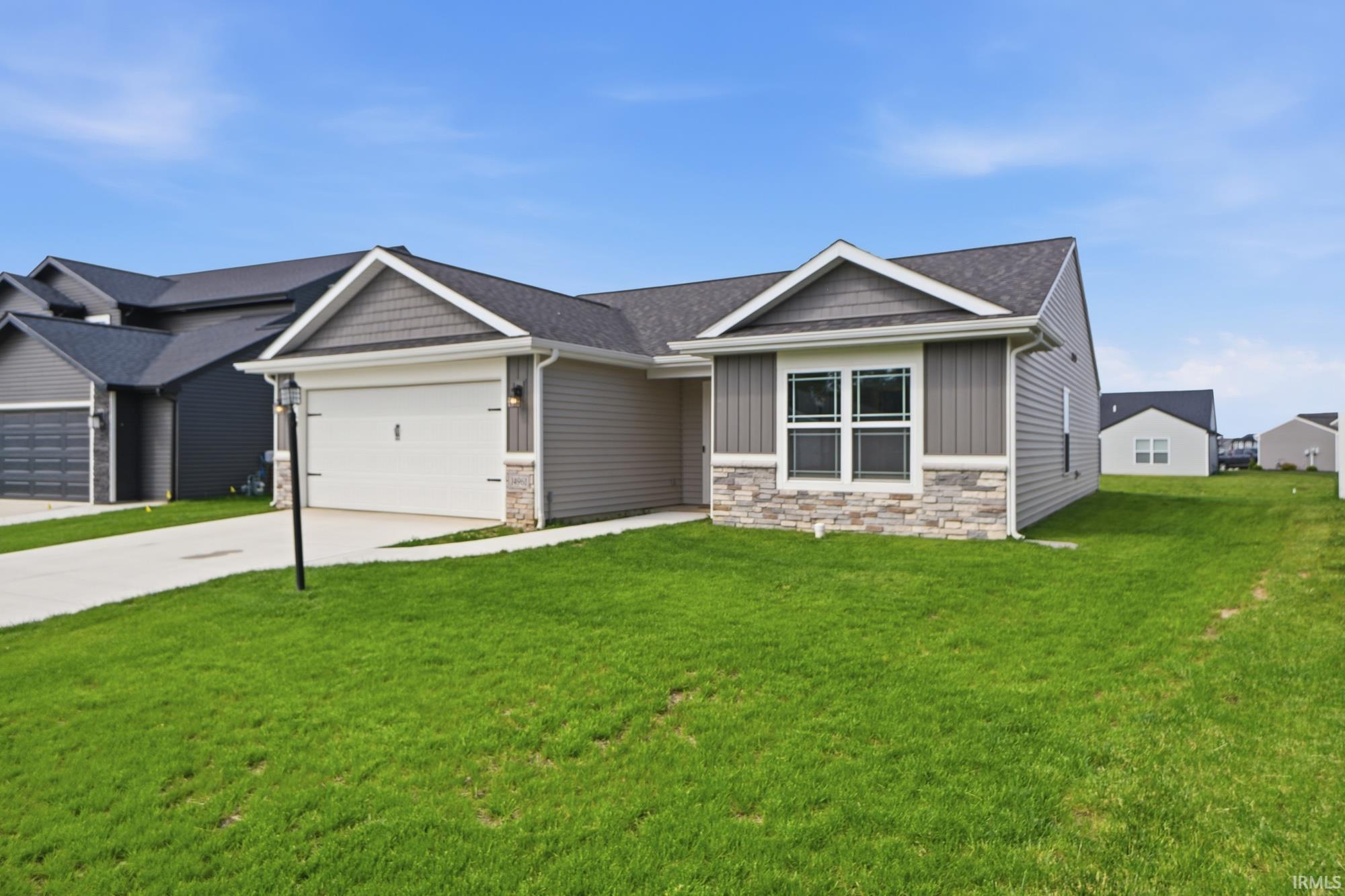 Ranch-style residence featuring a gray siding exterior with stone veneer accents and a dark shingle roof