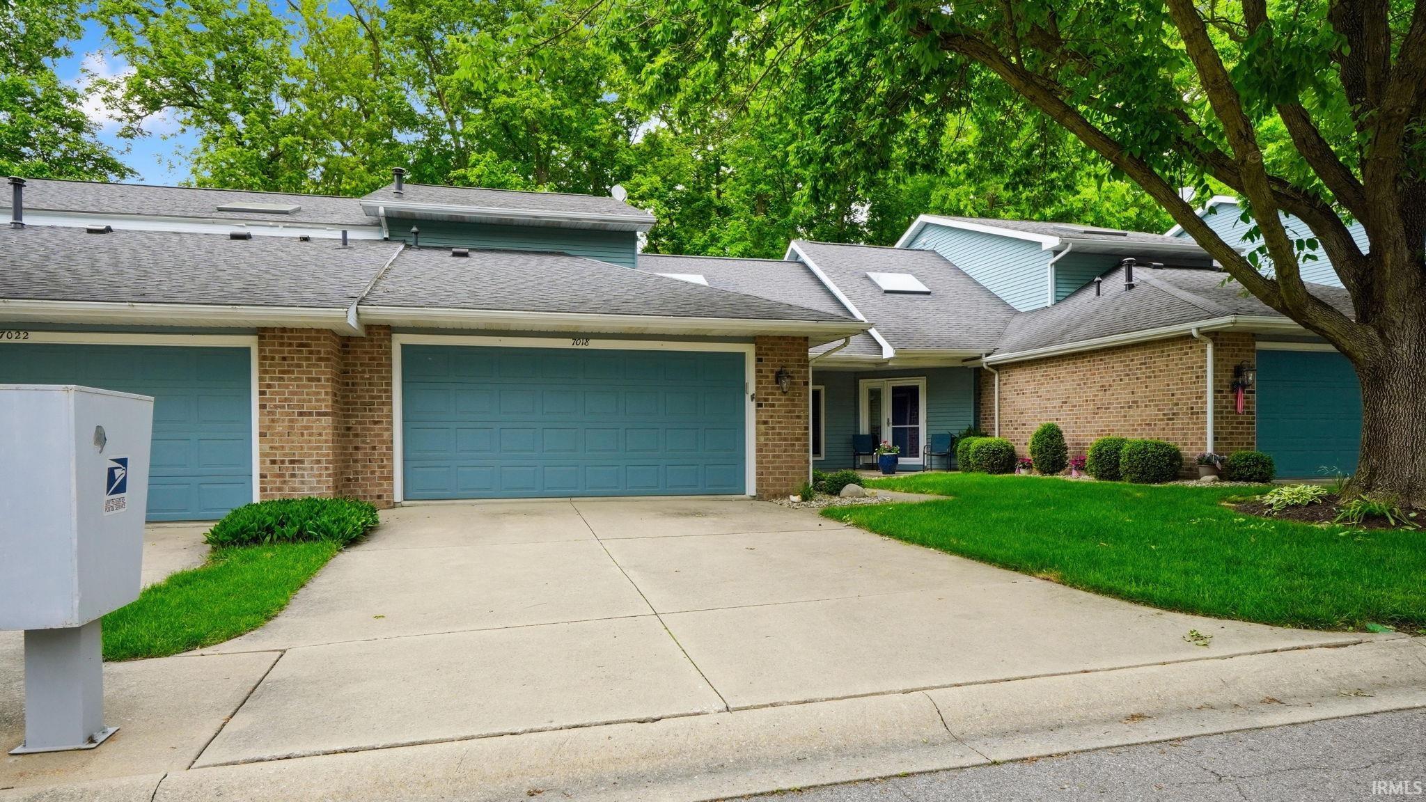 Exterior featuring a light blue facade with brick accents and two attached garages
