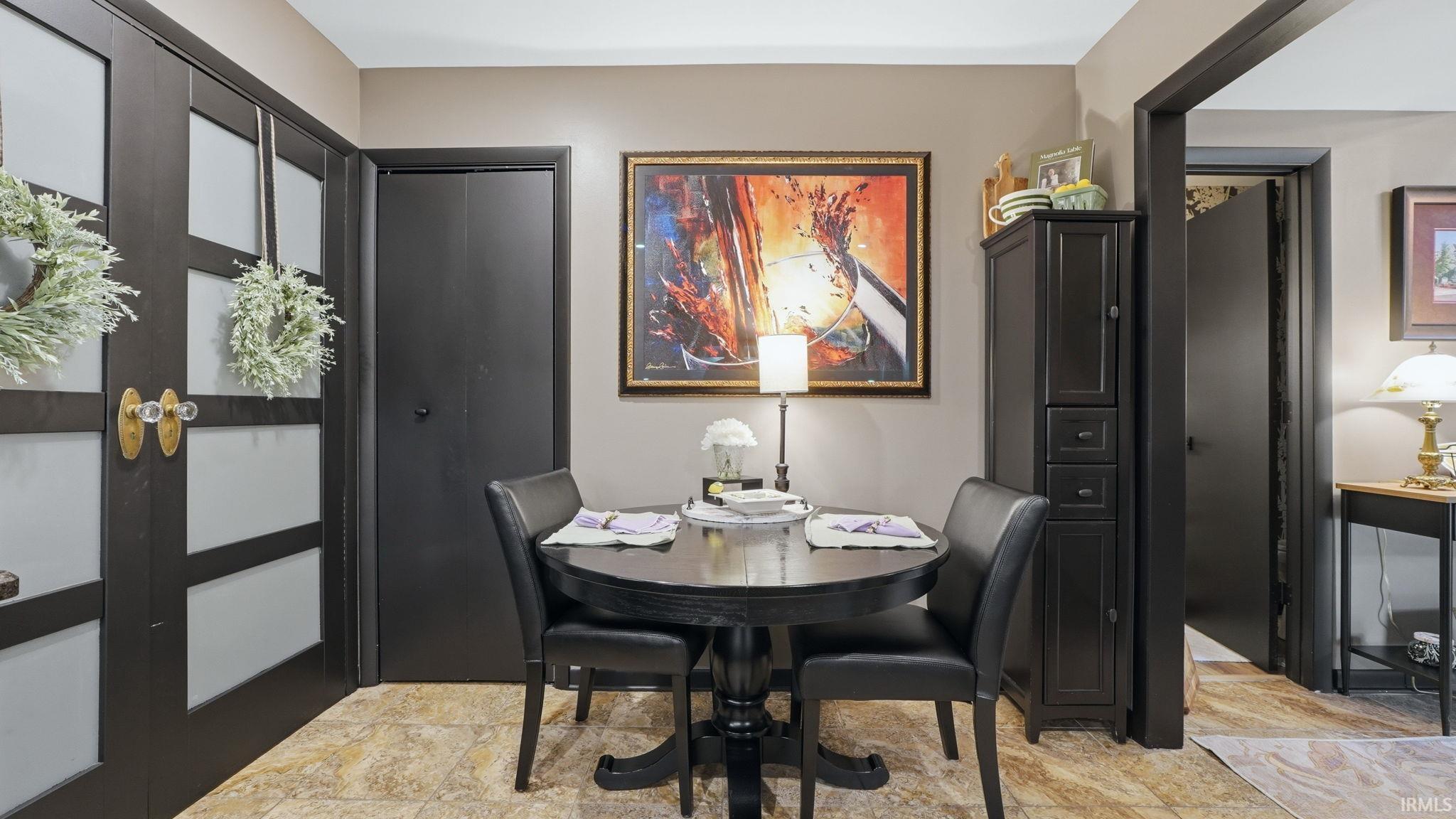 Dining area featuring a round pedestal table, black paneled doors with frosted glass inserts, and light-toned flooring