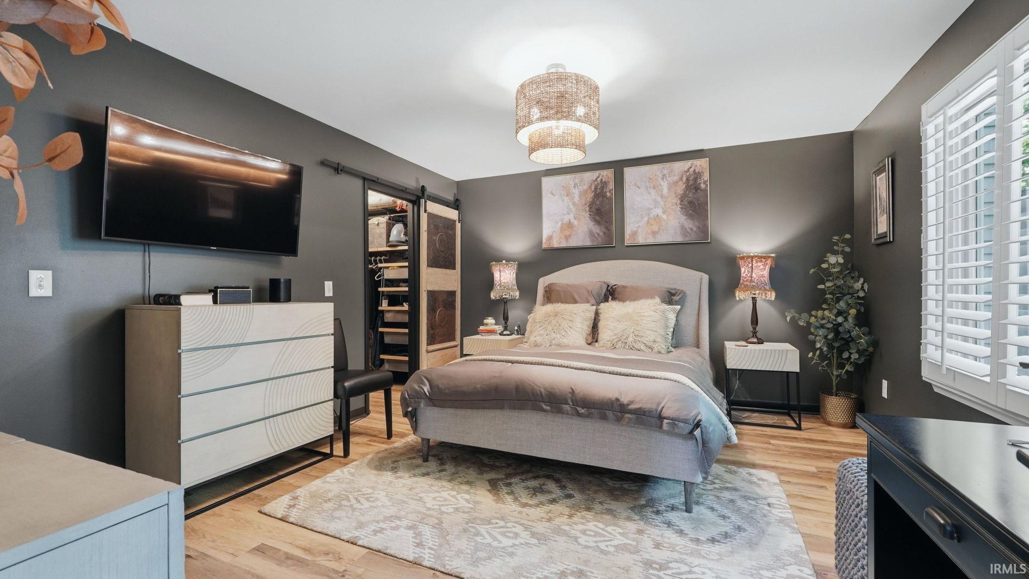 Spacious room featuring wood-finish flooring, a contemporary ceiling light fixture, and a sliding barn door